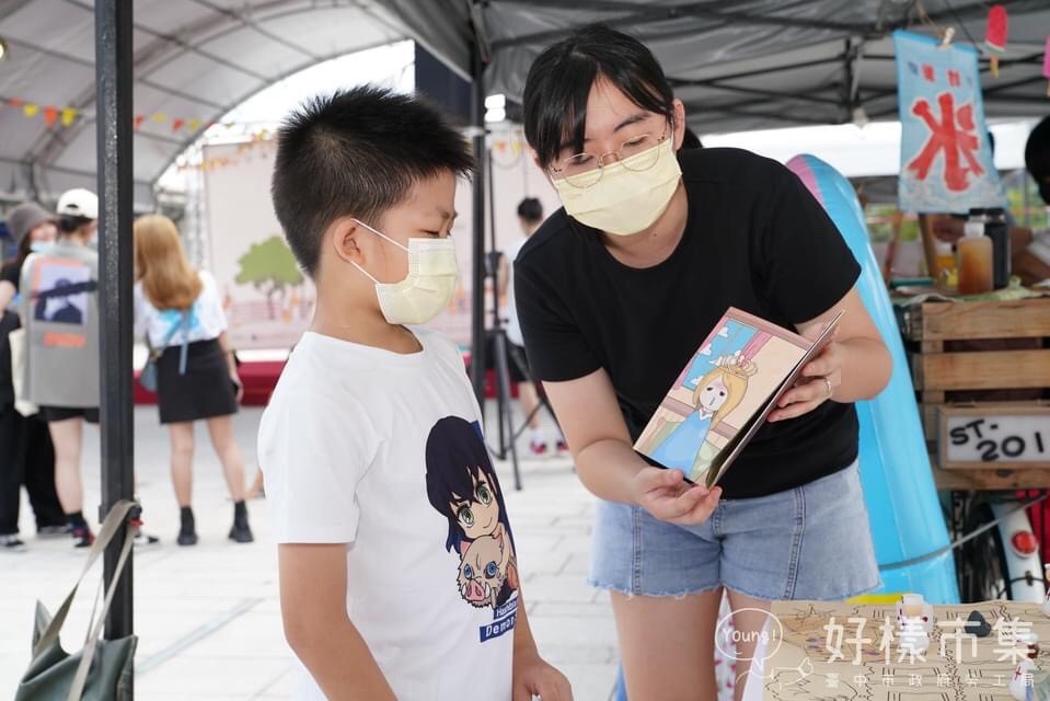 幼教系林孟諠同學(右)翻著自己繪製的畫本向小朋友解說。