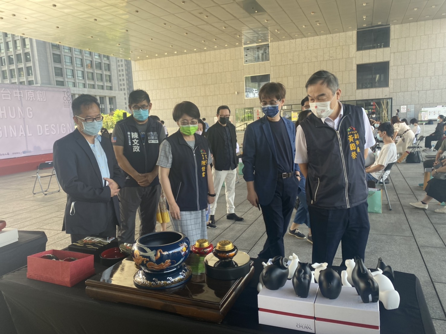 張峻嘉老師(左1)為黃國榮副市長(左4)、鄧成連副校長(左2)及台中市文化局長陳佳君(左3)解說入選商品。