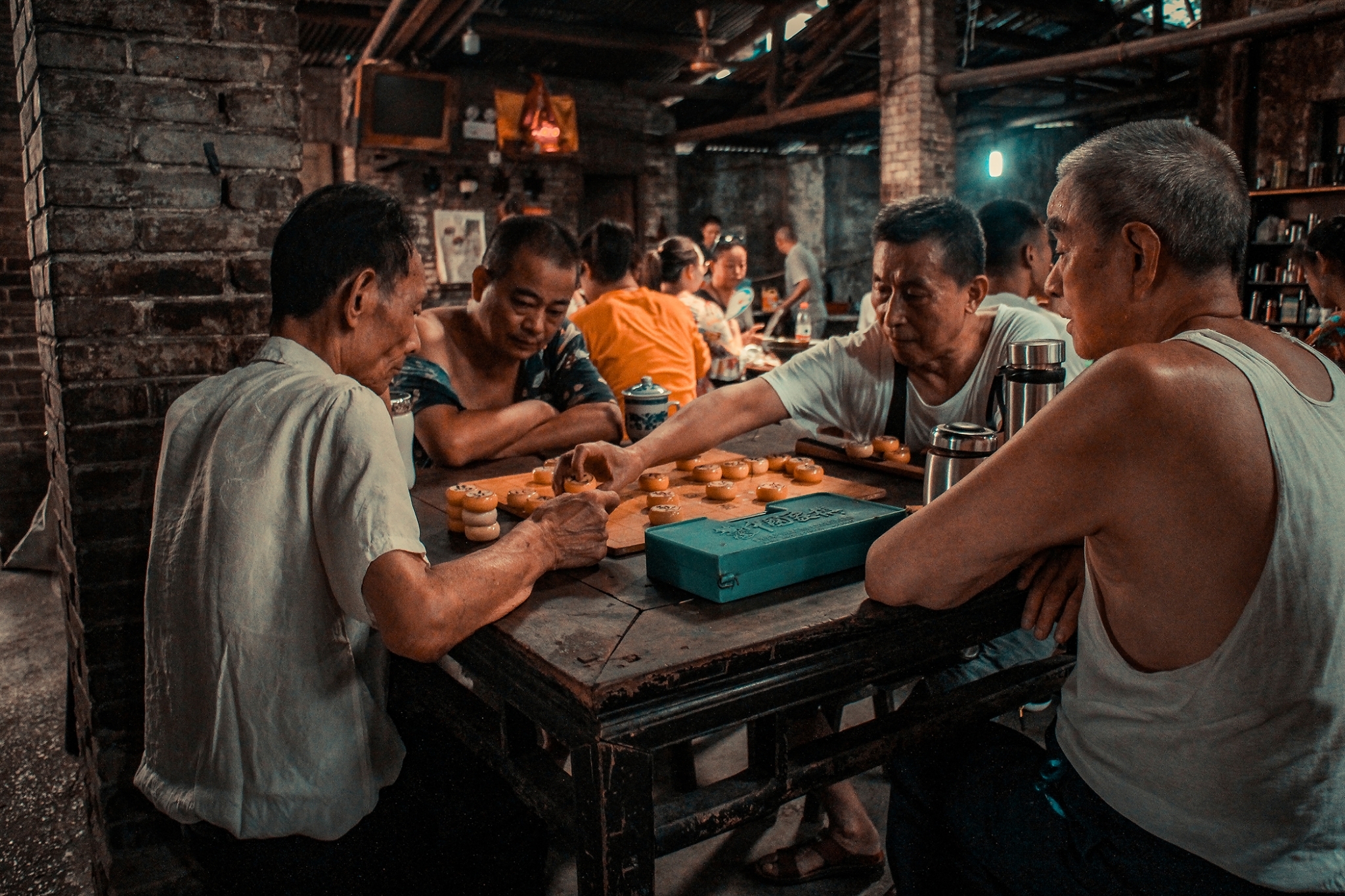 林駿騰「專注」系列作品之一,兩位民眾認真下棋,旁觀者凝神觀戰。呈現下棋者的「全神」與旁觀者的「貫注」。