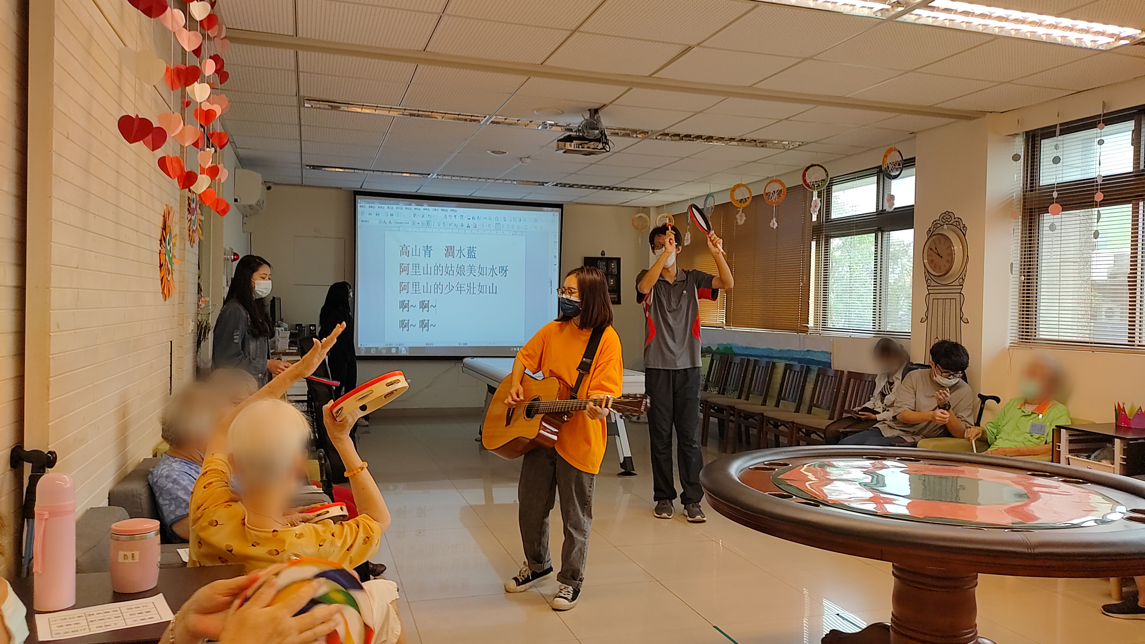 參加音樂治療工作坊的亞大學生至失智老人據點,運用課程所學,帶領高齡者玩起鈴鼓,接受音樂治療。