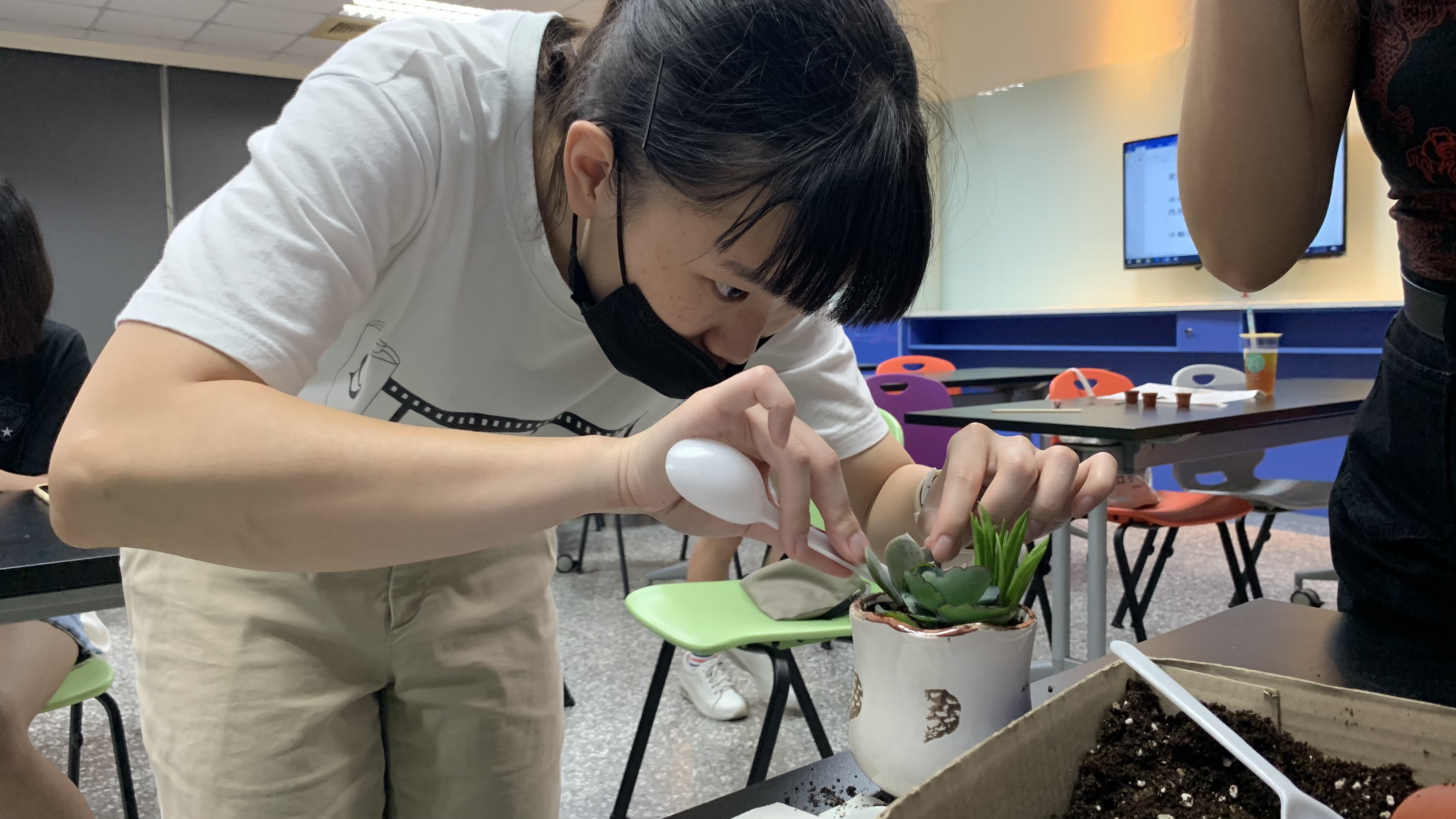 參加「綠手指療癒多肉組盆」課程的同學,將土壤平鋪並固定多肉植物。