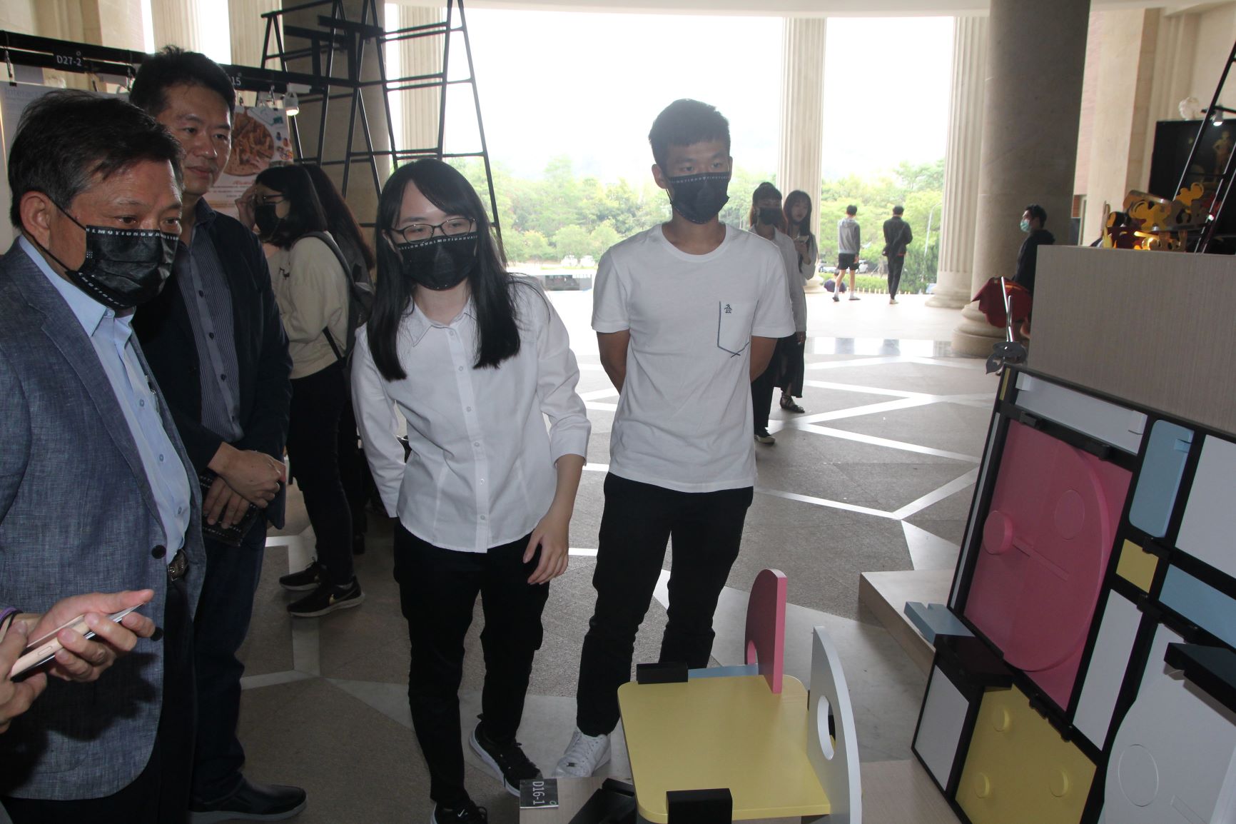 中新科技公司董事長江舟陣(左)在商設系主任林信宏(左2)陪同下,聽取學生解說設計理念。