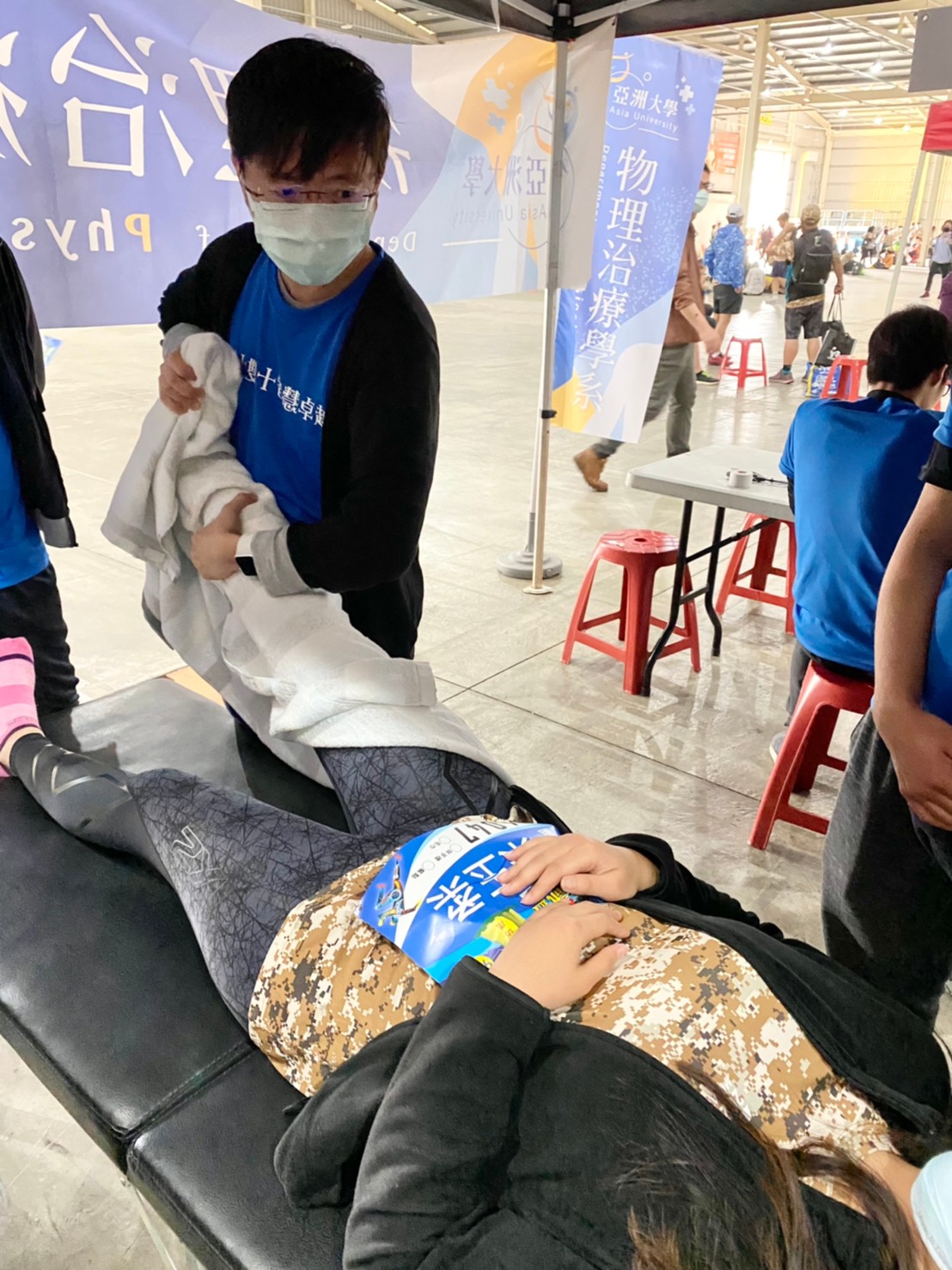 亞大物治系老師陳彥年,協助跑完馬拉松比賽的跑者,緩解賽後小腿抽筋問題。