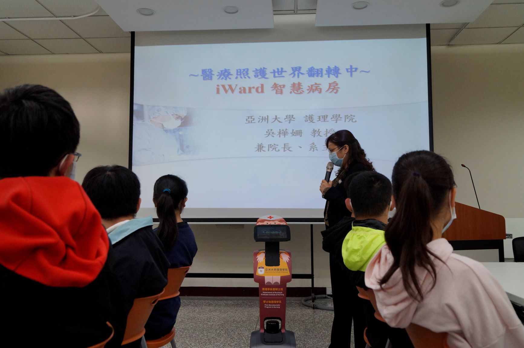 亞大「AI醫療營隊」的學員們,1月31日上午參觀護理學院,看到吳樺姍院長(站立者)與Temi照護機器人進行語音互動,都覺得十分有趣。