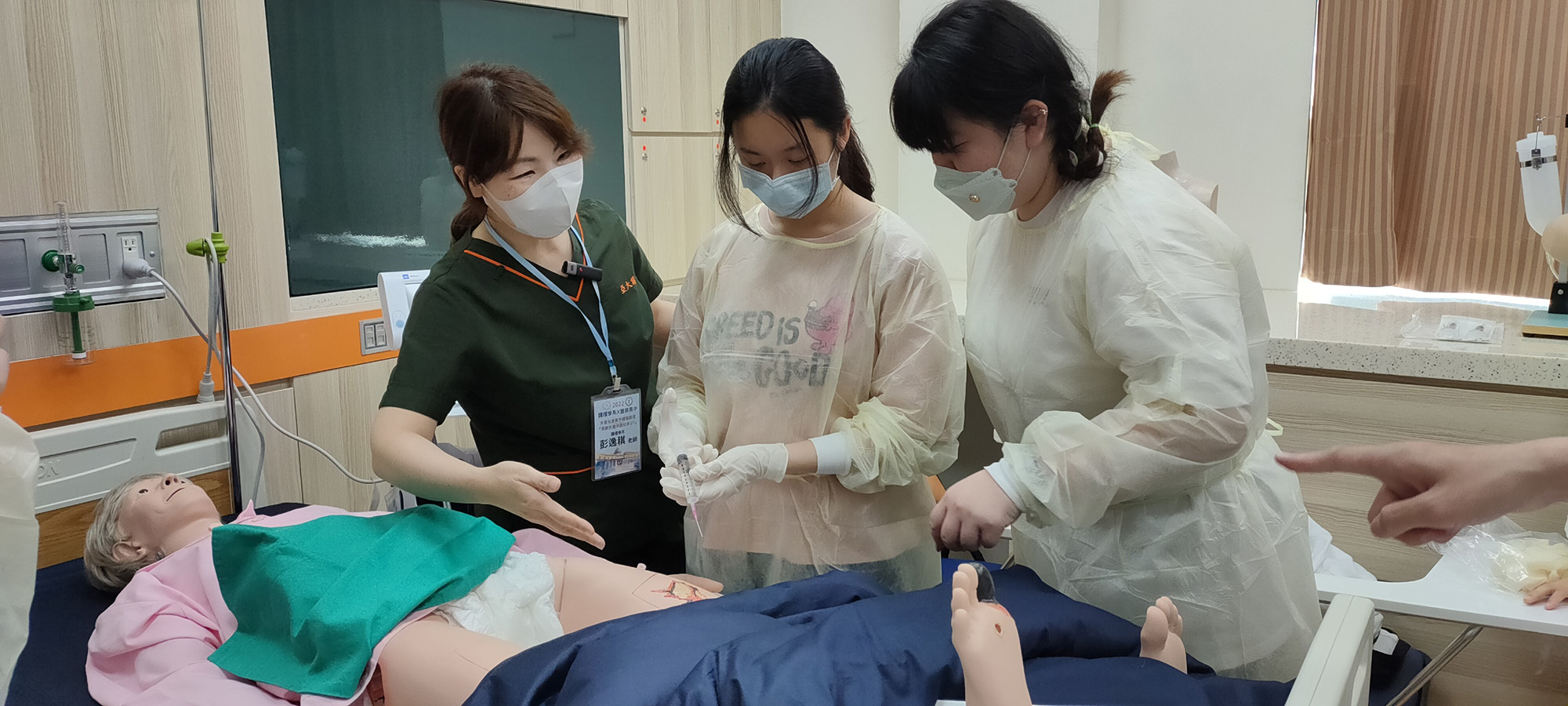 亞大護理學系老師彭逸稘(左),於智慧病房模擬高齡失智長者壓瘡傷口,分組帶領學員傷口清創實作