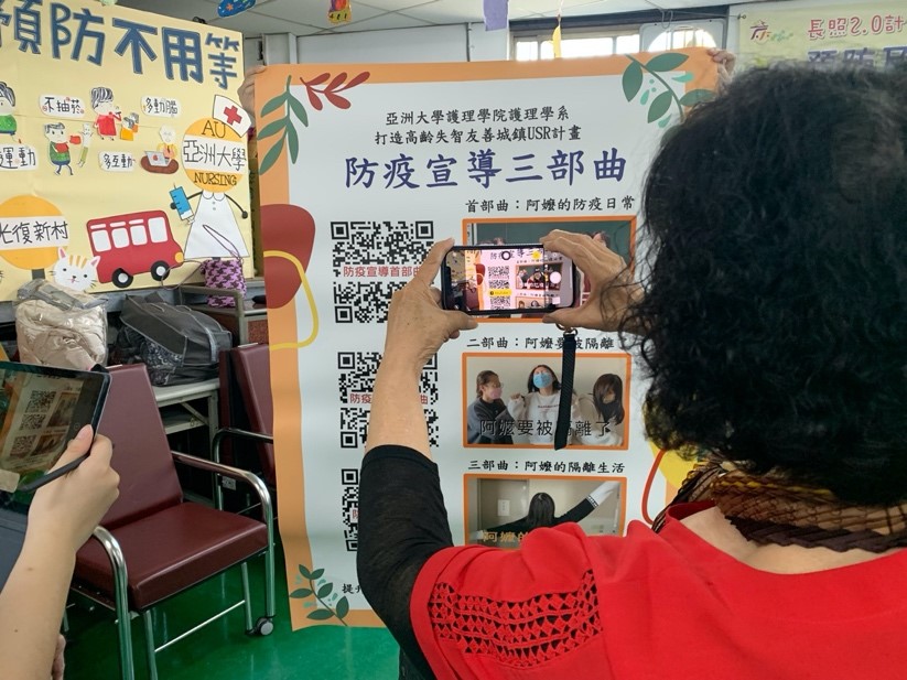 圖為社區關懷據點長輩運用手機掃描AR marker,觀看大專生專題計畫所開發之台語防疫宣導AR影片