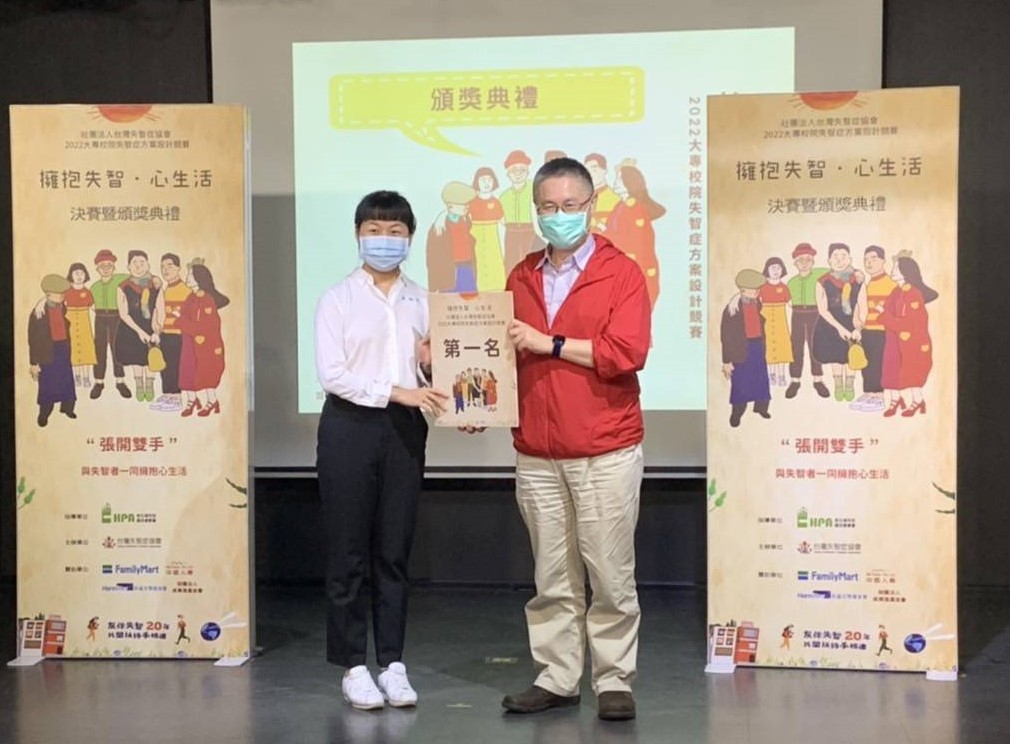 圖為亞大護理系同學張祖兒(左),代表上台獲頒「擁抱失智 · 心生活- 2022大專院校失智症方案設計競賽」第1名獎狀