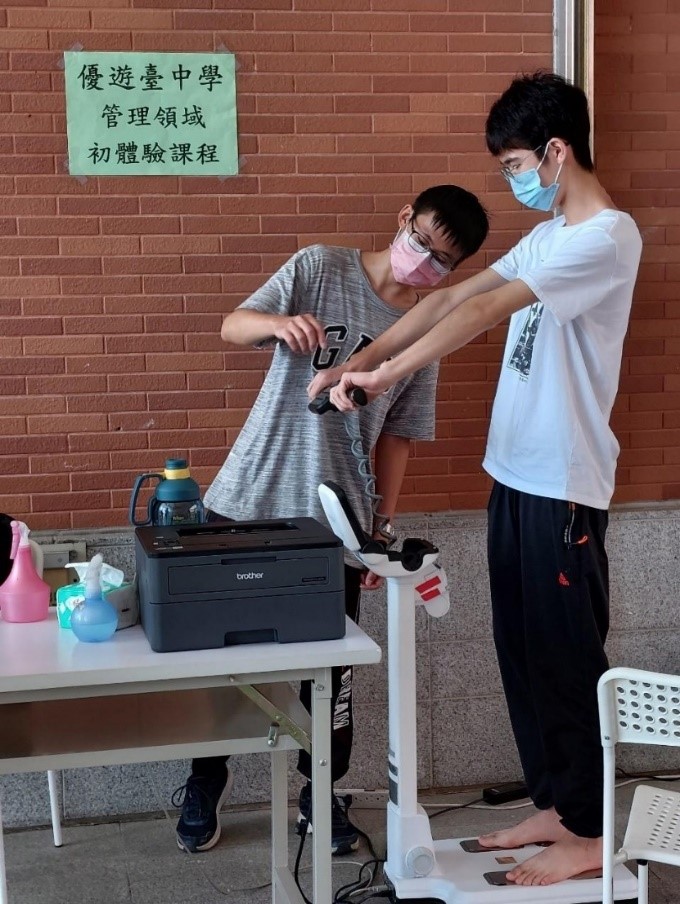 圖為亞大休憩系的「幸福製造所-探索休憩戶外實境遊戲」,引導高中生使用「InBody」身體組成分析儀,施測身體狀況。