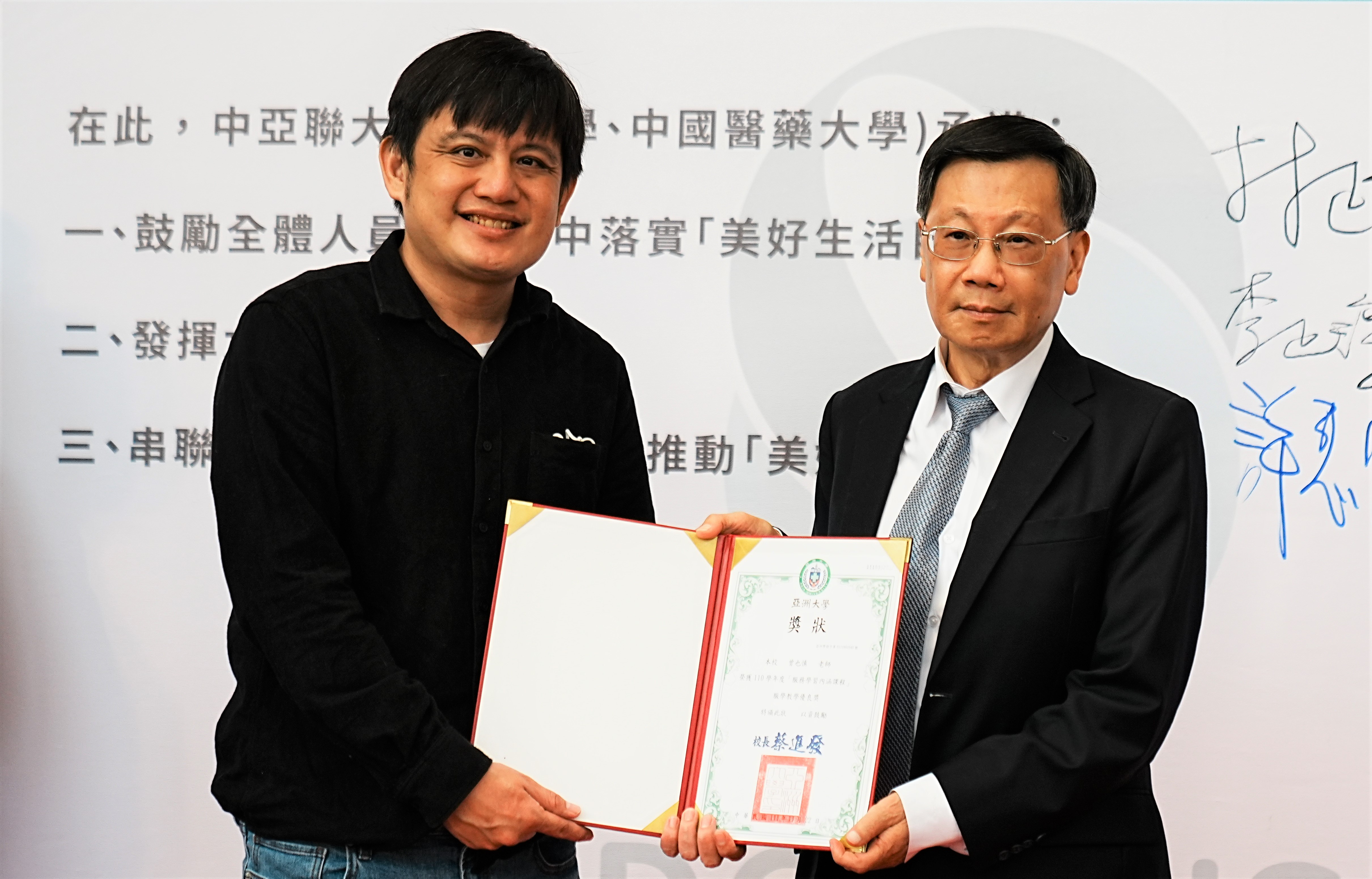 圖為亞大校長蔡進發(右),頒發「服務學習內涵課程」教學優良獎,給資傳系老師曾也慎。