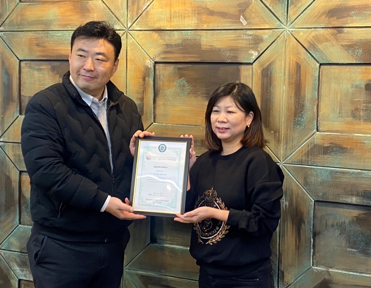 圖為亞大商設系老師劉芃均(右)致贈感謝狀,給慶一大學孫勇浩院長。