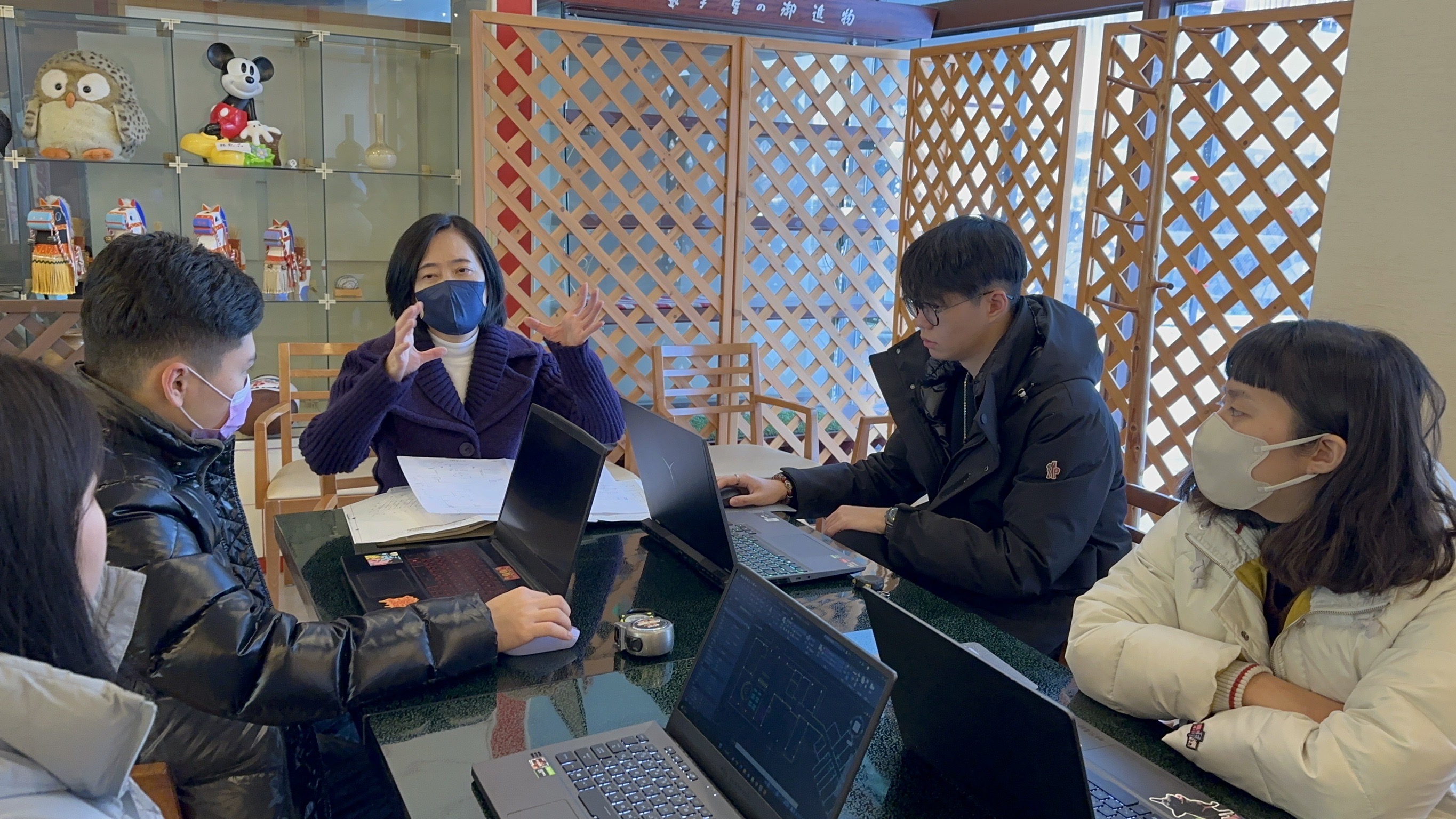 圖為亞大室設系老師林佳慧(中),與4位研習同學討論飯店設計。