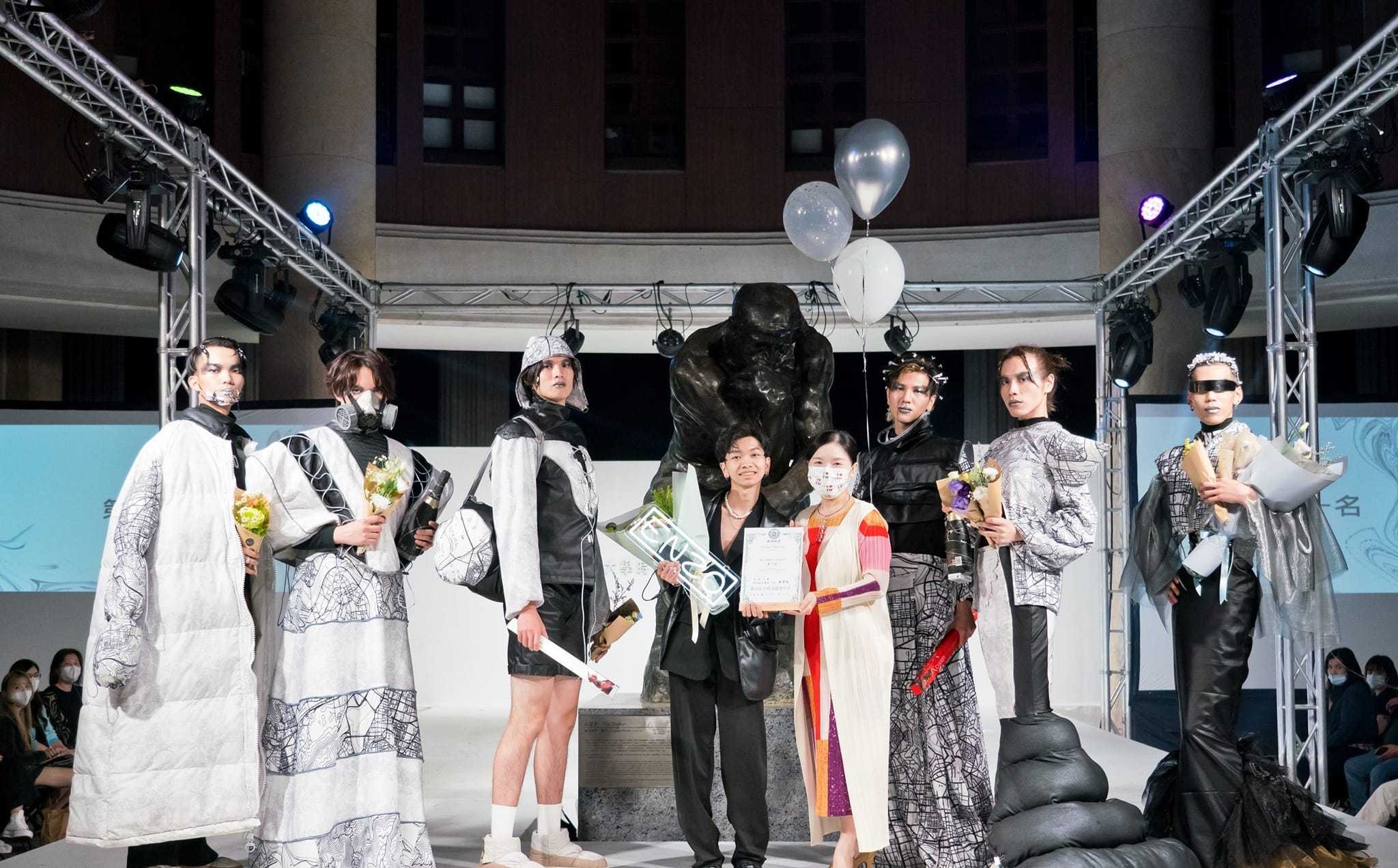 圖為亞大時尚系主任林青玫(右4),頒獎給服裝組高行佑同學(右5),他的作品「同溫層 echo chamber」,獲第1名。