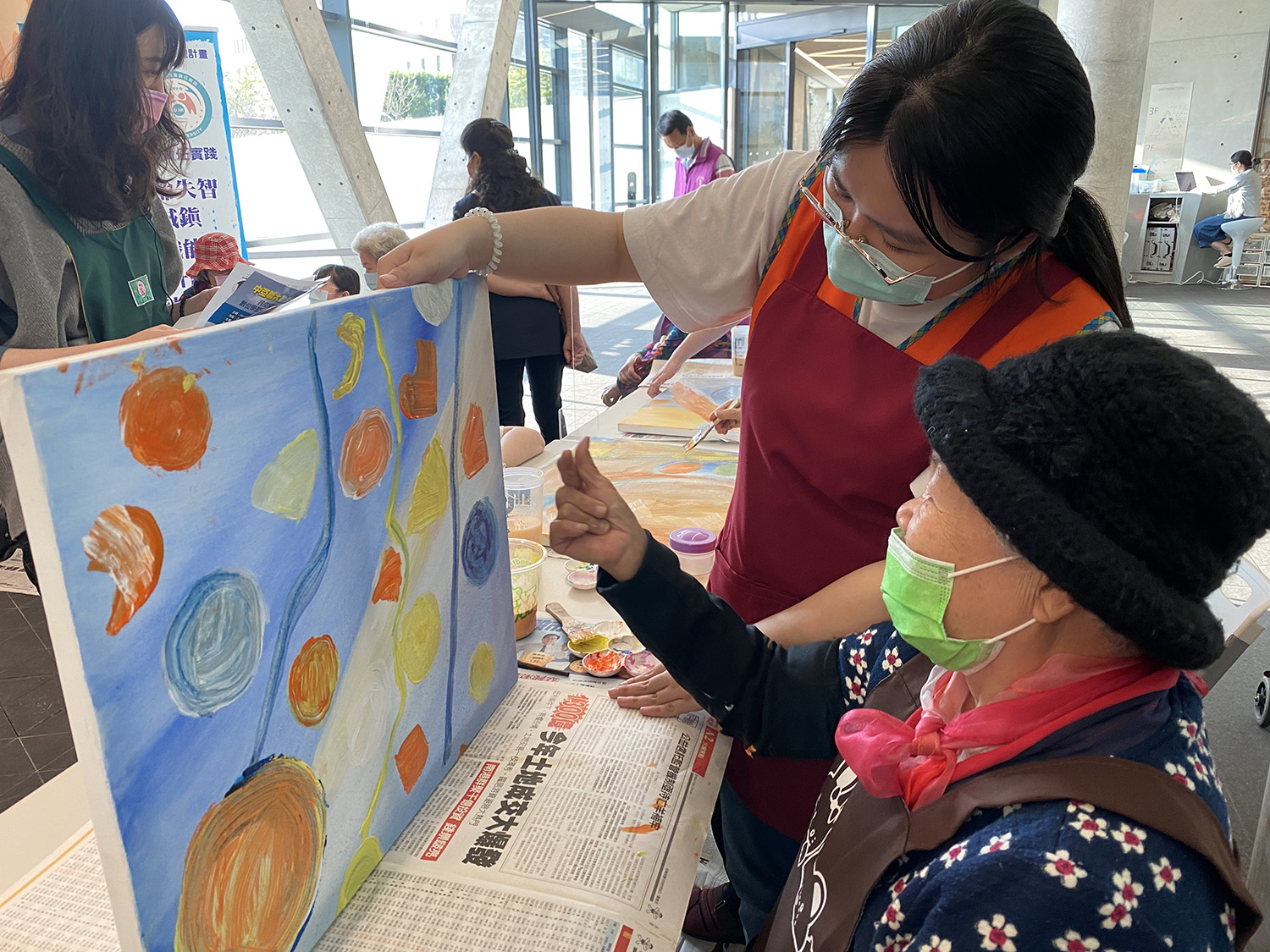 圖為失智長輩持失智友善藝術處方箋進入亞美館看展,亞大護理系同學協助失智長輩做藝術輔療。