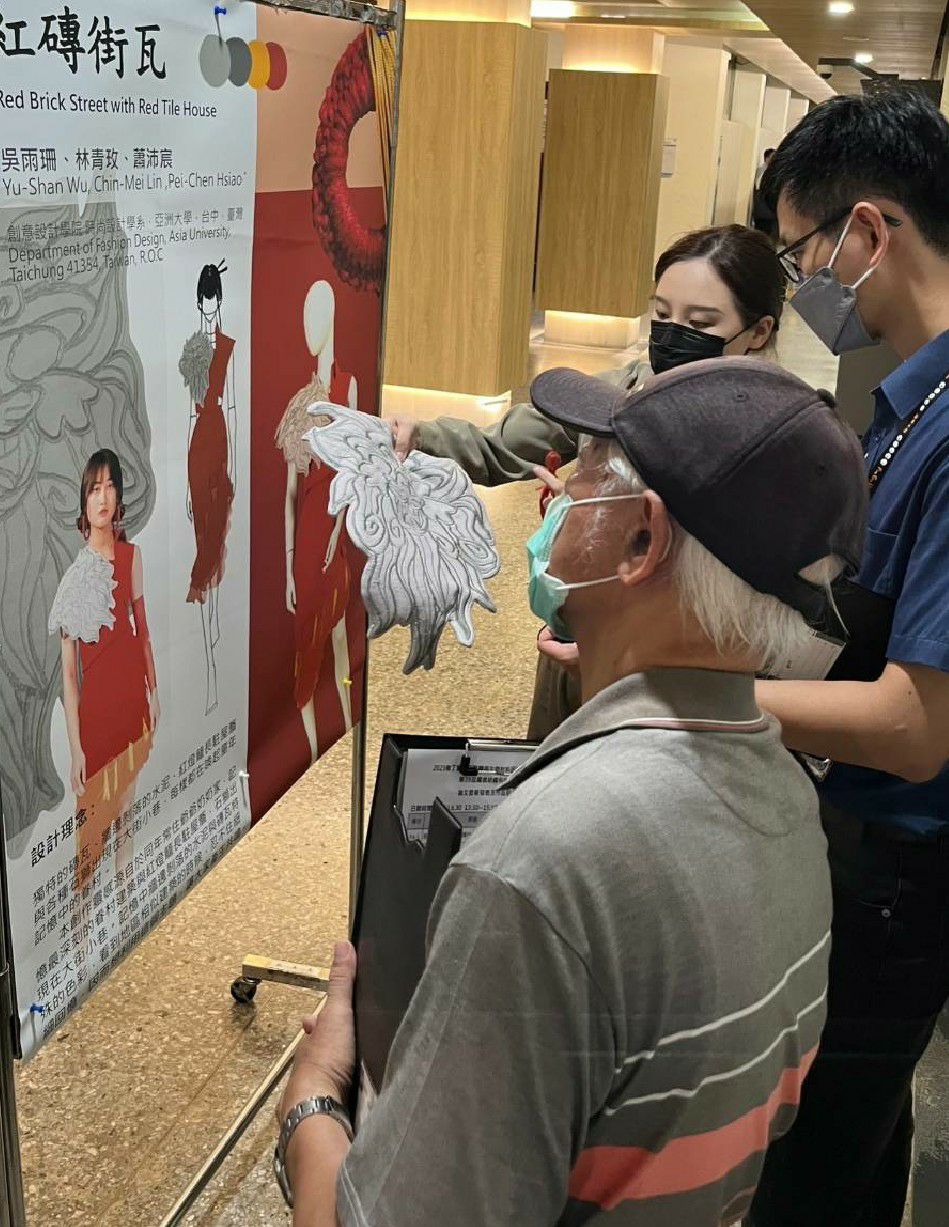 圖為亞大時尚系同學,向評審解說服飾創作設計壁報發表。
