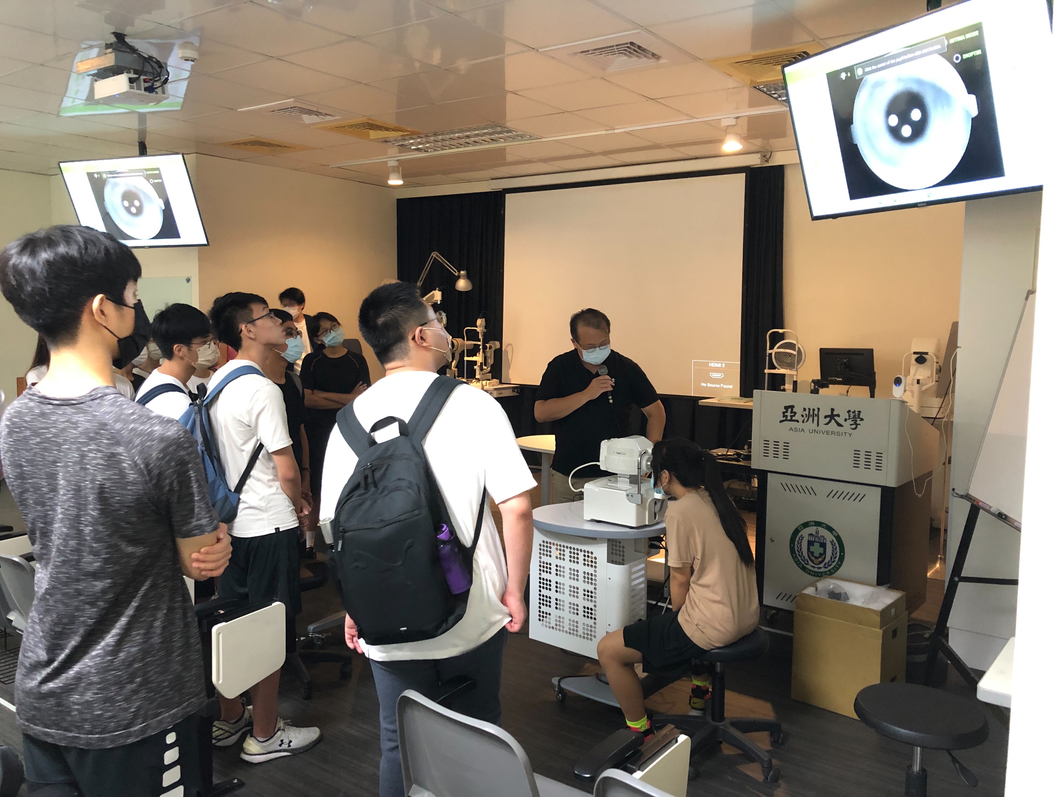 圖為亞大視光系主任曾榮凱,帶領同學體驗「眼底照相機」,了解視網膜結構及功能。