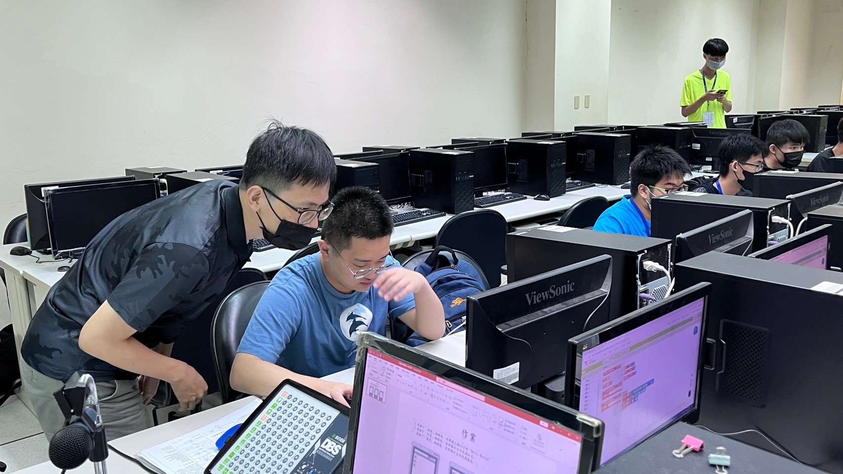 圖為亞大生醫系胡文品老師(左),在APP開發介紹課程中,讓同學實際操作製作簡單的小遊戲。