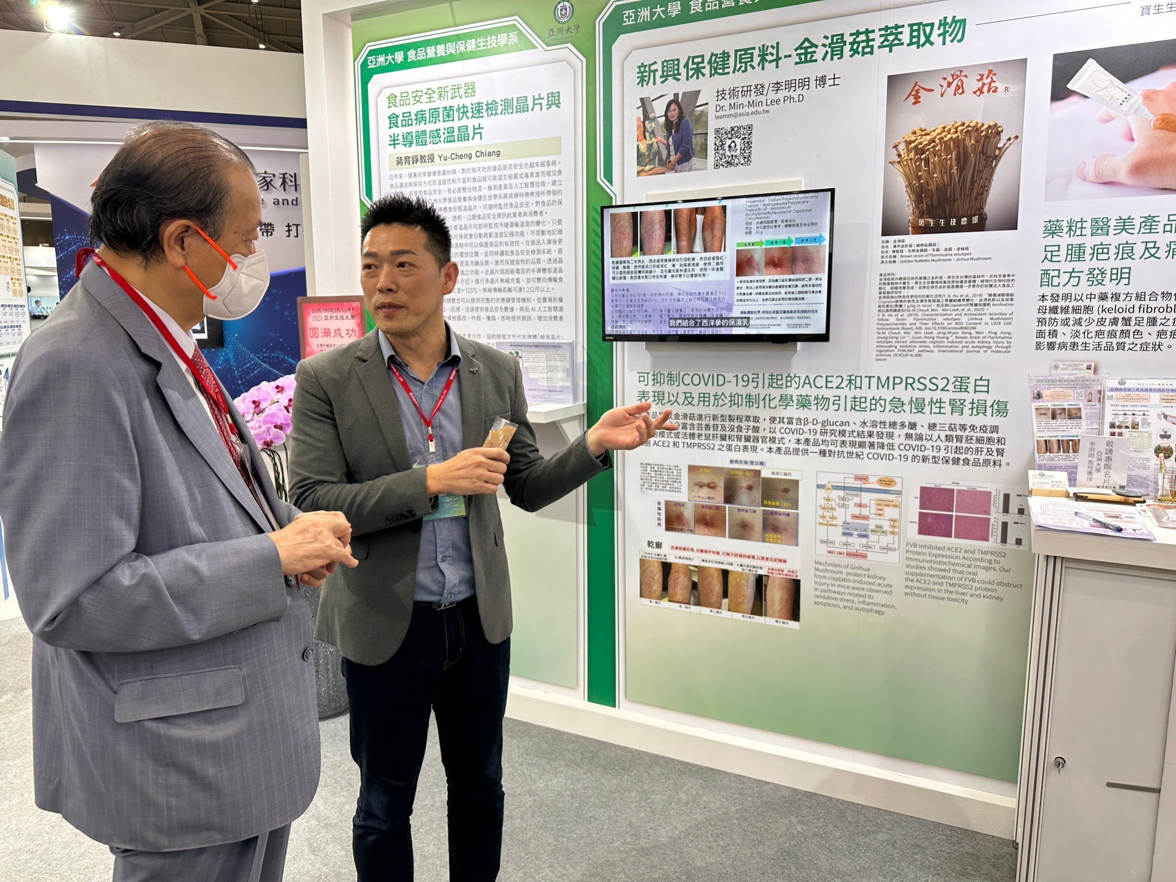 圖為亞大創辦人蔡長海博士(左)在「2023亞洲生技大展」現場,聆聽亞大研究生吳文良解說「改善蟹足腫疤痕的配方產品」研究成效。