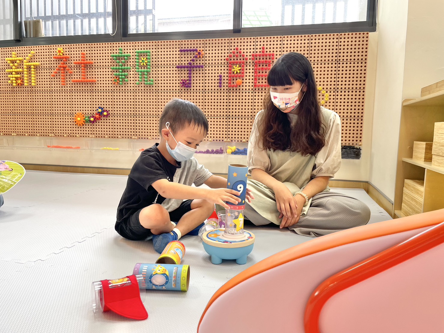 圖為新社親子館啟用,遊戲區教保員與幼兒互動。