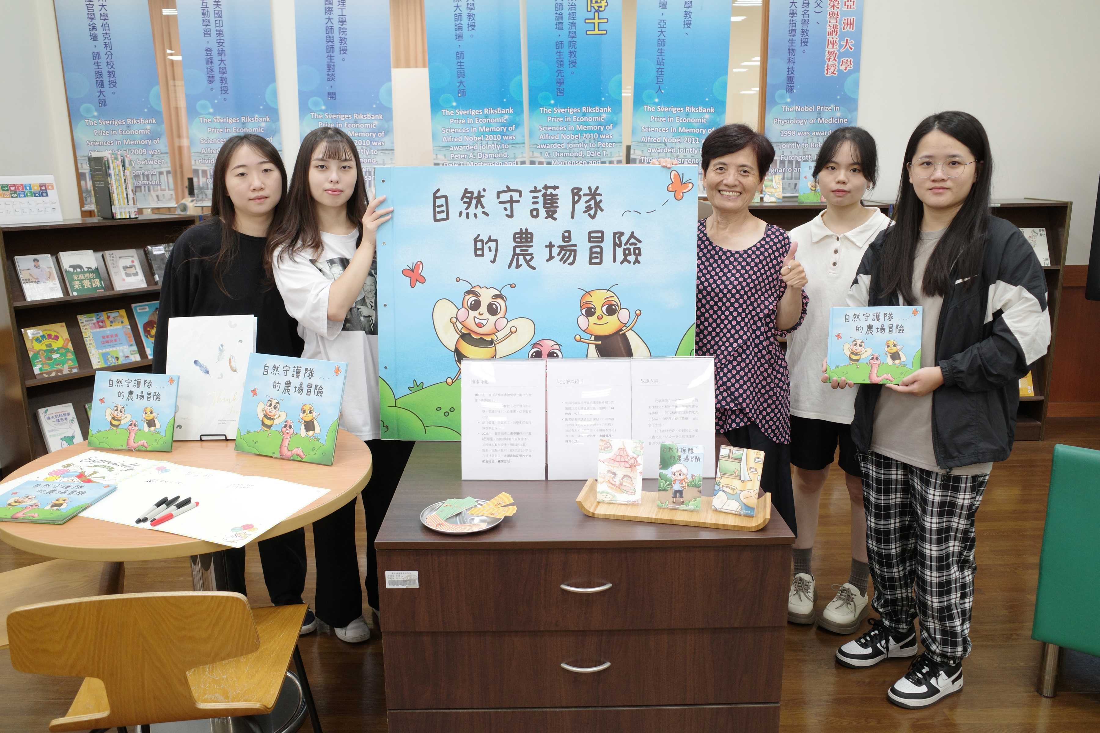圖為亞大圖書館長廖淑娟(右3),與書香學伴小組成員在作品展區前合影。