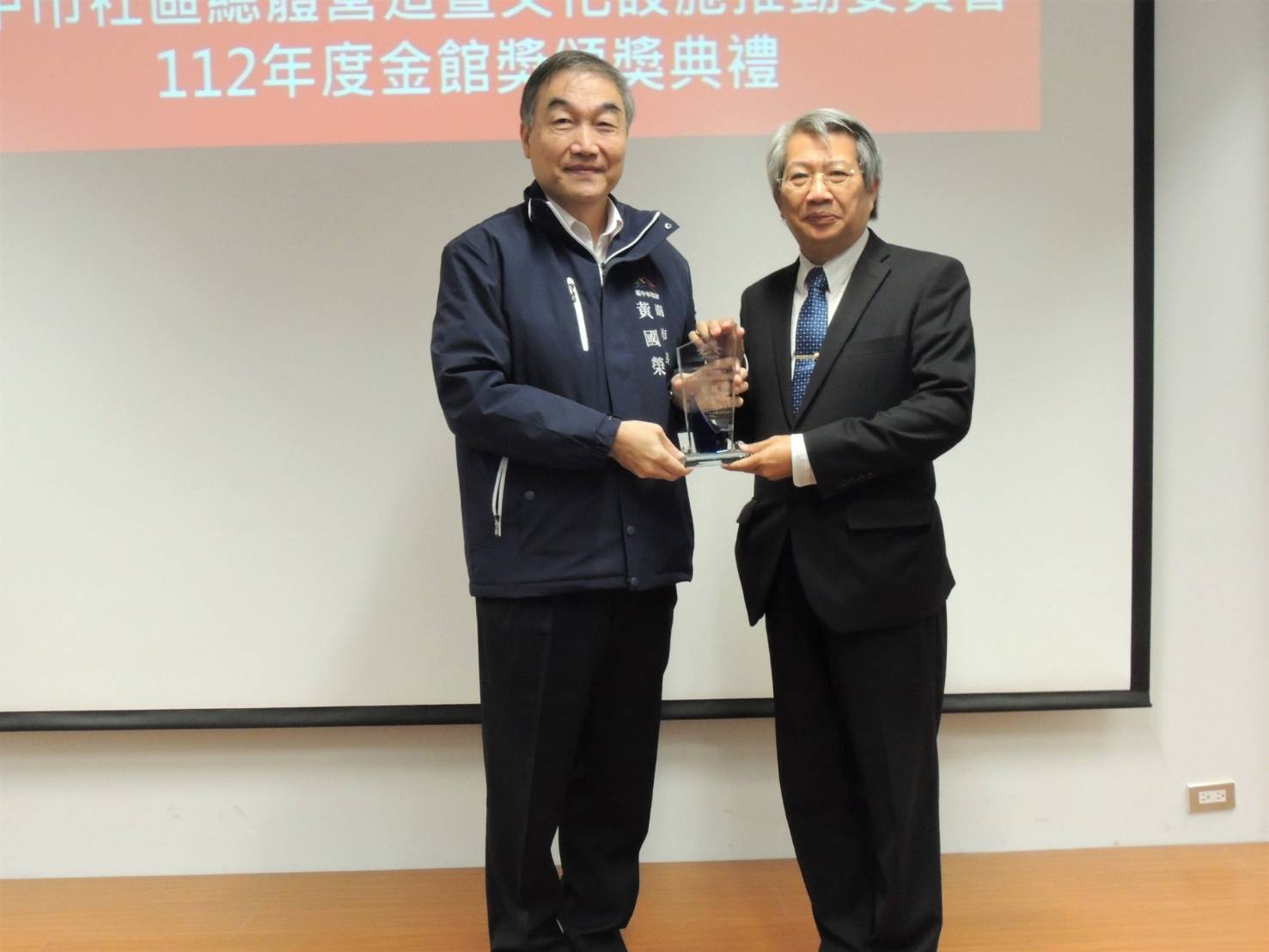 圖為台中市副市長黃國榮(左)頒發「金館獎」,由亞美館長潘襎代表領獎。