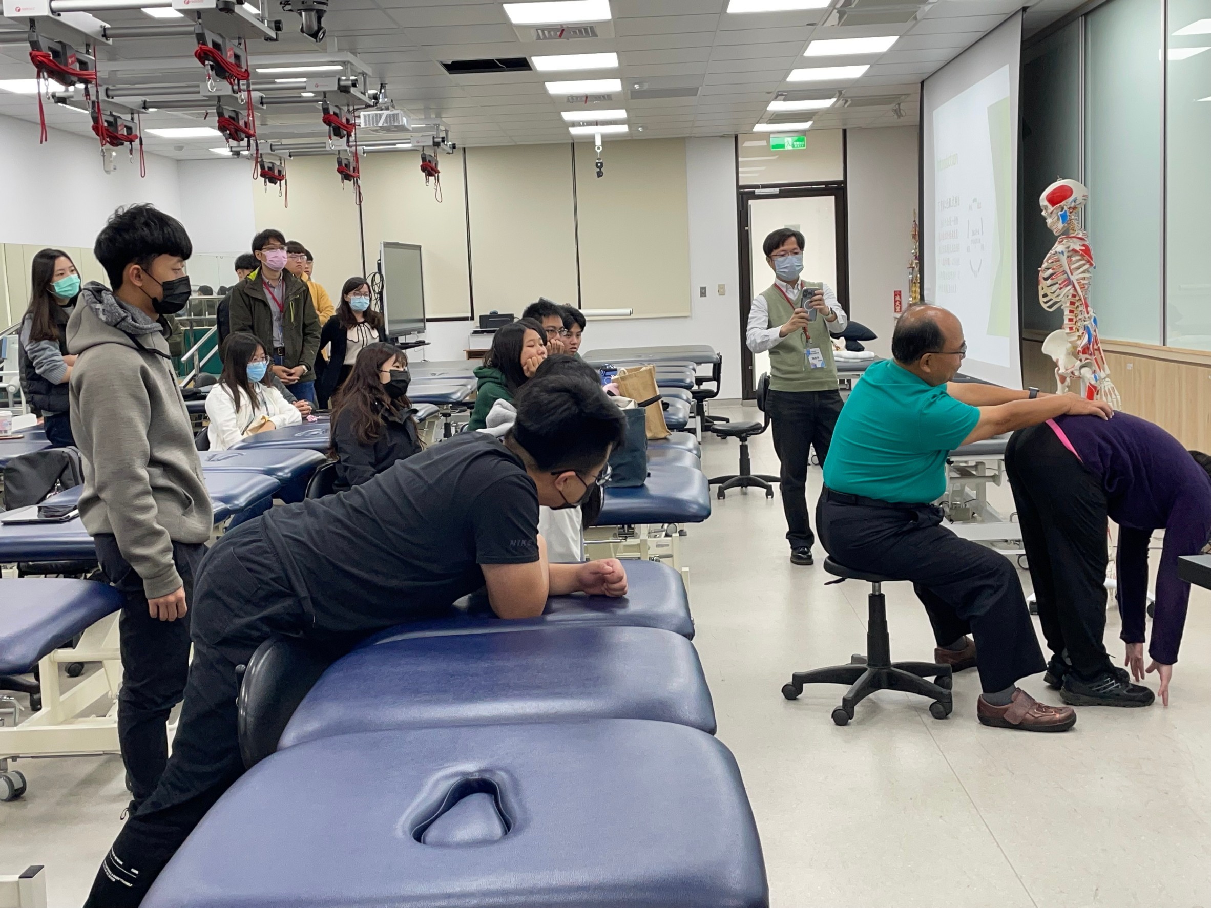 圖為張光銀物理治療師示範徒手治療,亞大物治系友、在校同學認真聆聽觀摩。