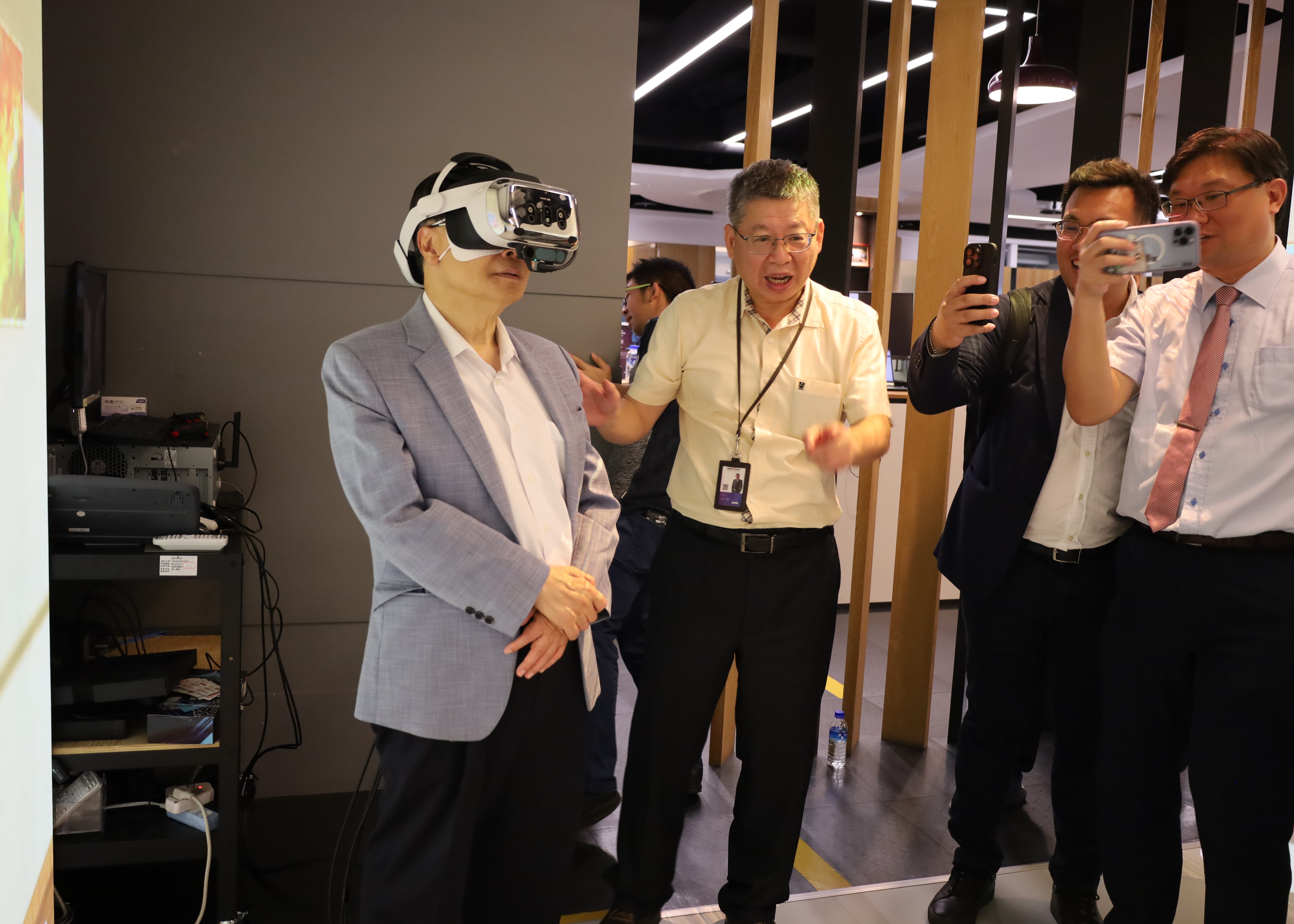 亞大校長蔡進發(左),體驗配戴佐臻最高階的「Varjo XR-4」穿戴式顯示器,佐臻董事長梁文隆(左2)解說高水準的視覺保真度和沉浸感,應用於精密的工業操作。