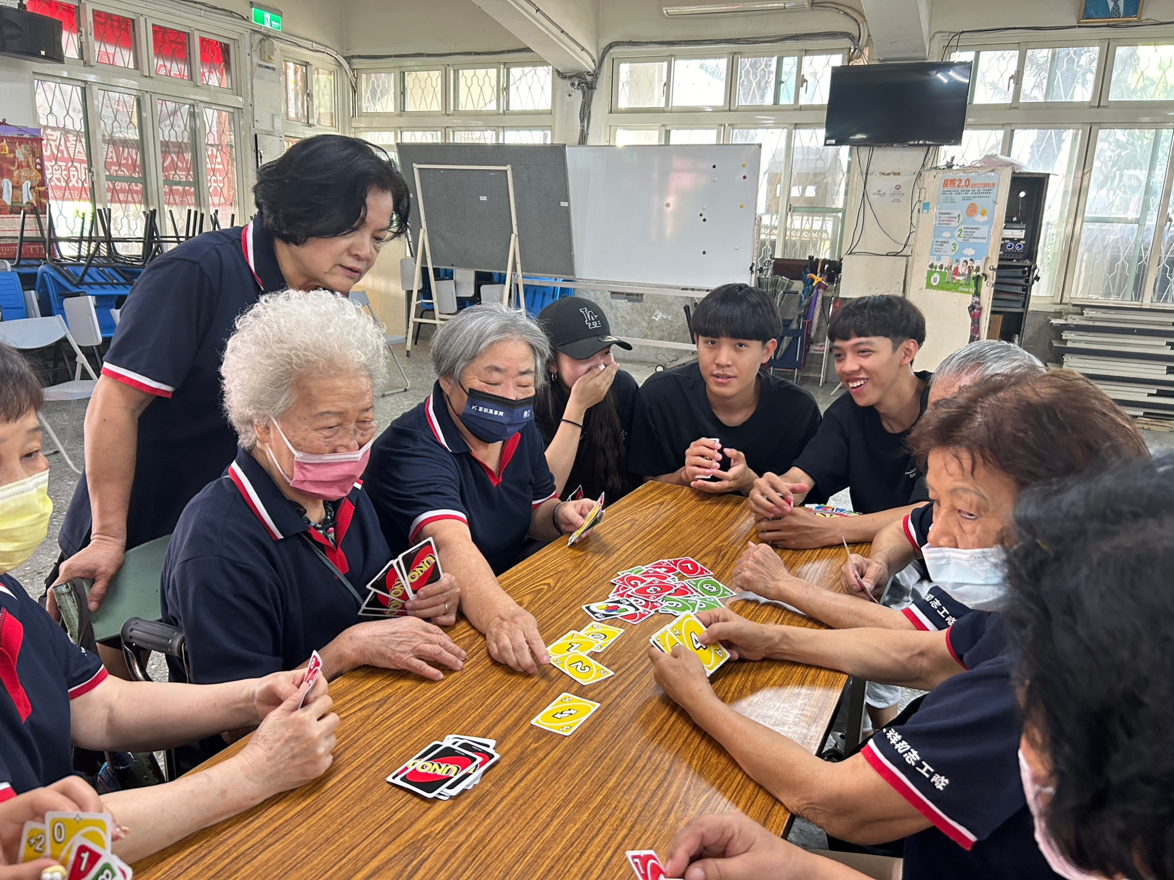 圖為亞大商設系同學,與新仁社區年長者一同玩UNO卡牌遊戲。