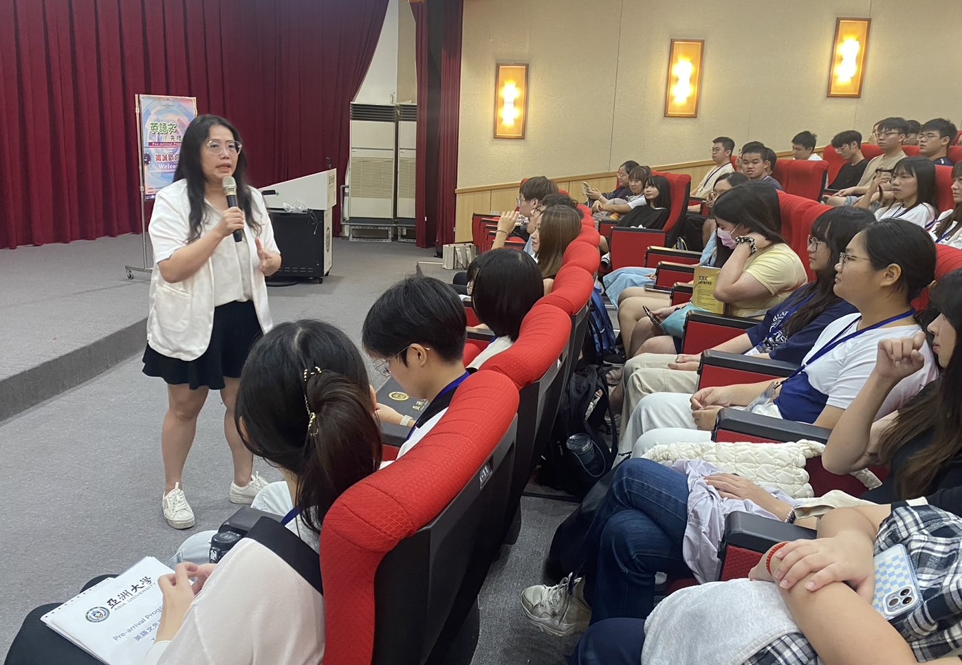 圖為亞大語發中心主任陳淑娟(站立者),在英語文先修營始業式鼓勵同學。