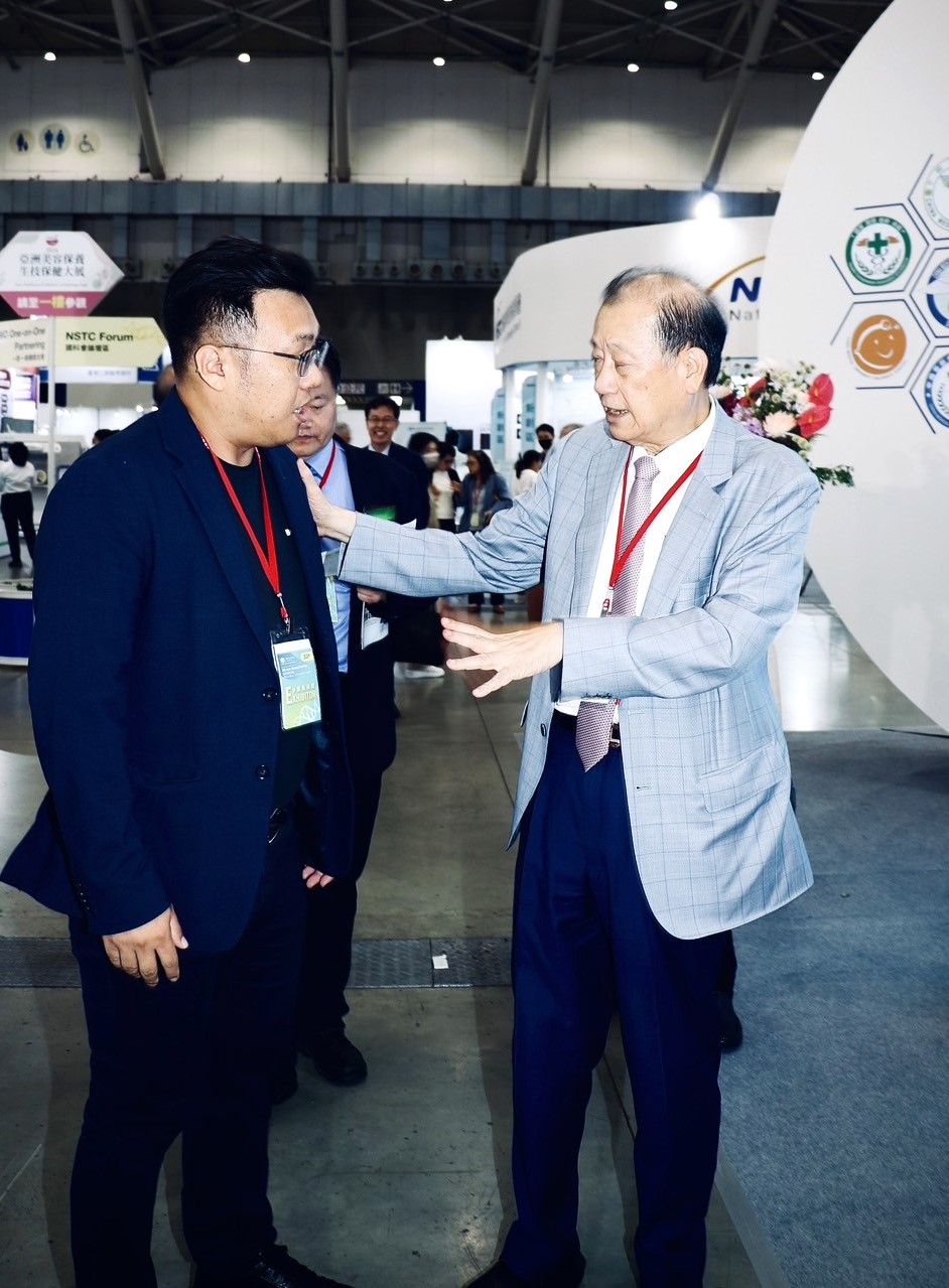 圖為亞大創辦人蔡長海(右),在生技展上與產學長王昭能(左)討論如何加速亞大智慧醫療的發展。