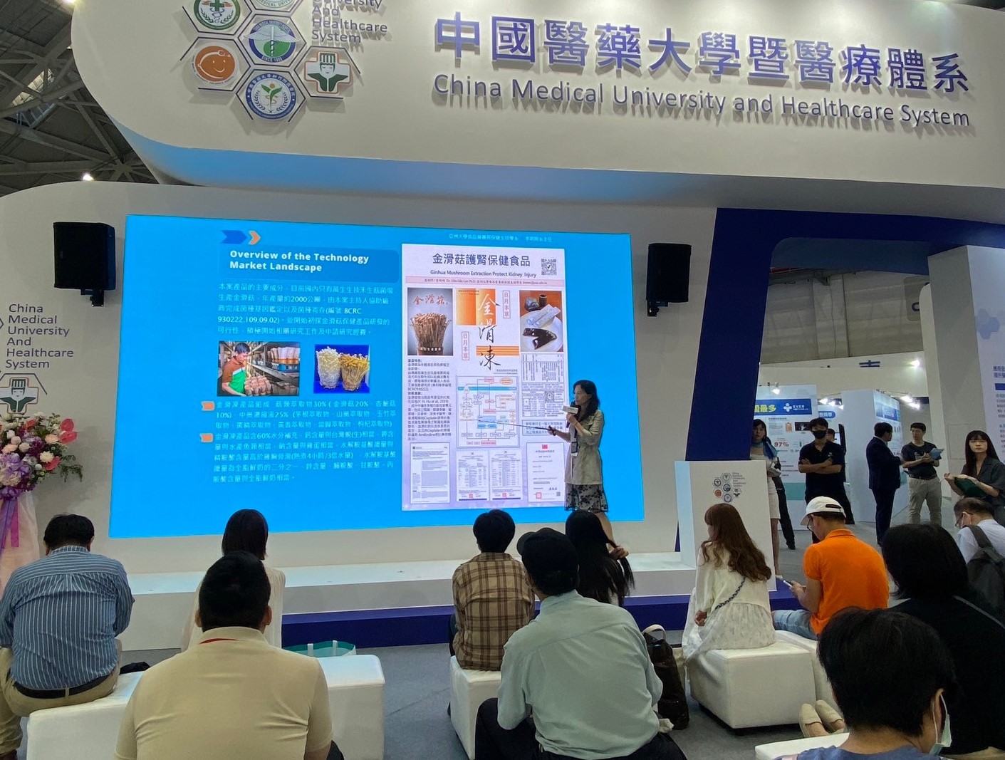 圖為亞大保健系主任李明明,在生技展上發表所展出的專利技術,吸引許多民眾駐足聆聽。