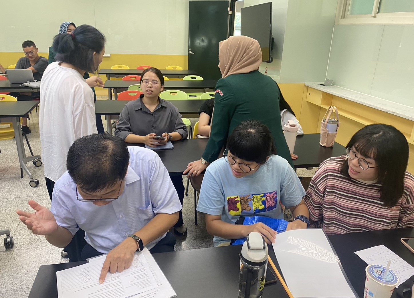 圖為亞大資工系主任朱學亭(前排左1),在印尼語結訓報告前,與其他學員認真練習講稿。