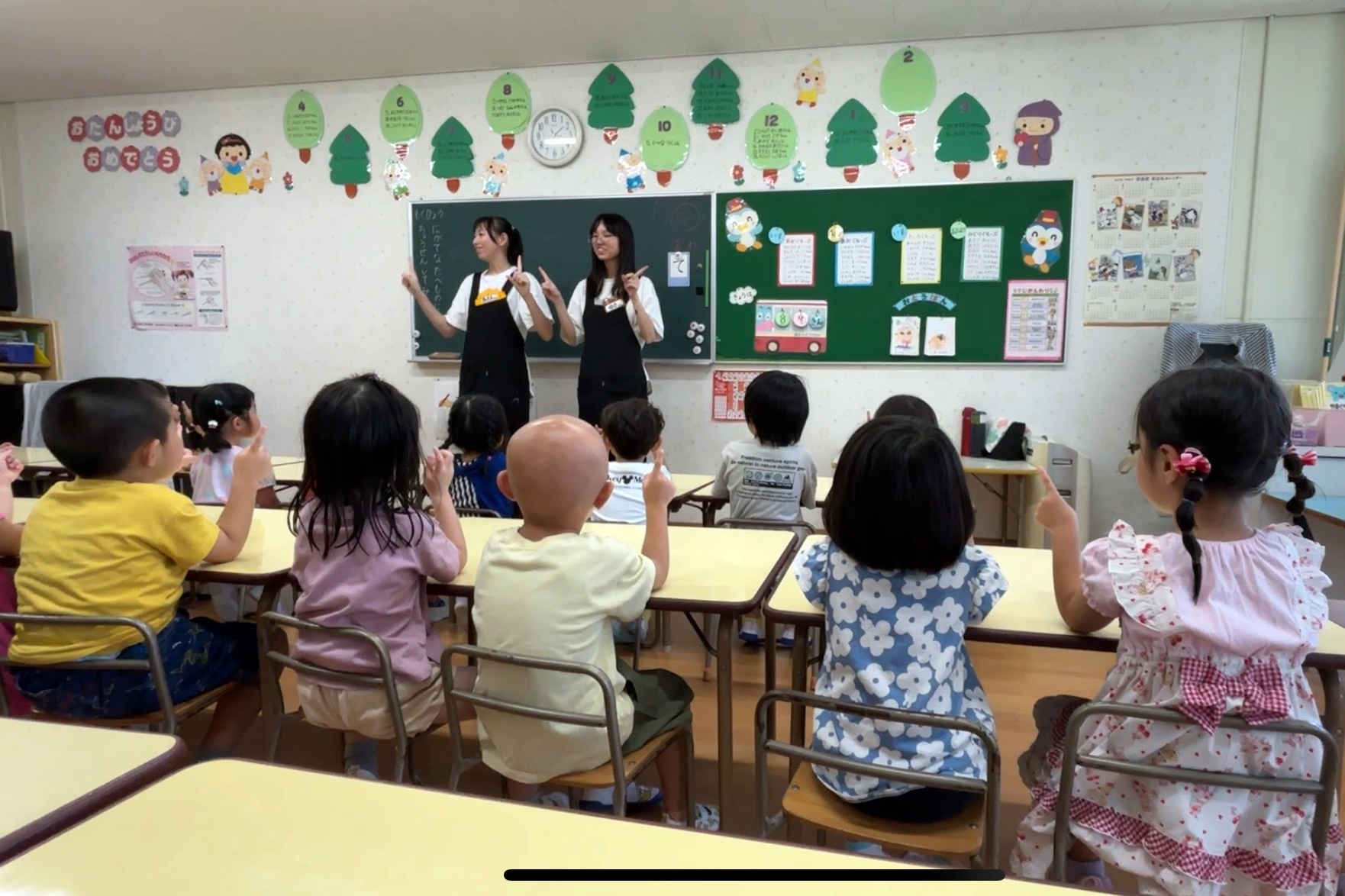 圖為亞大幼教系錢妤蓁(站立者右)、郭曉蓉(站立者左)同學,在日本實習時,以自編手指舞單元教導幼兒律動。