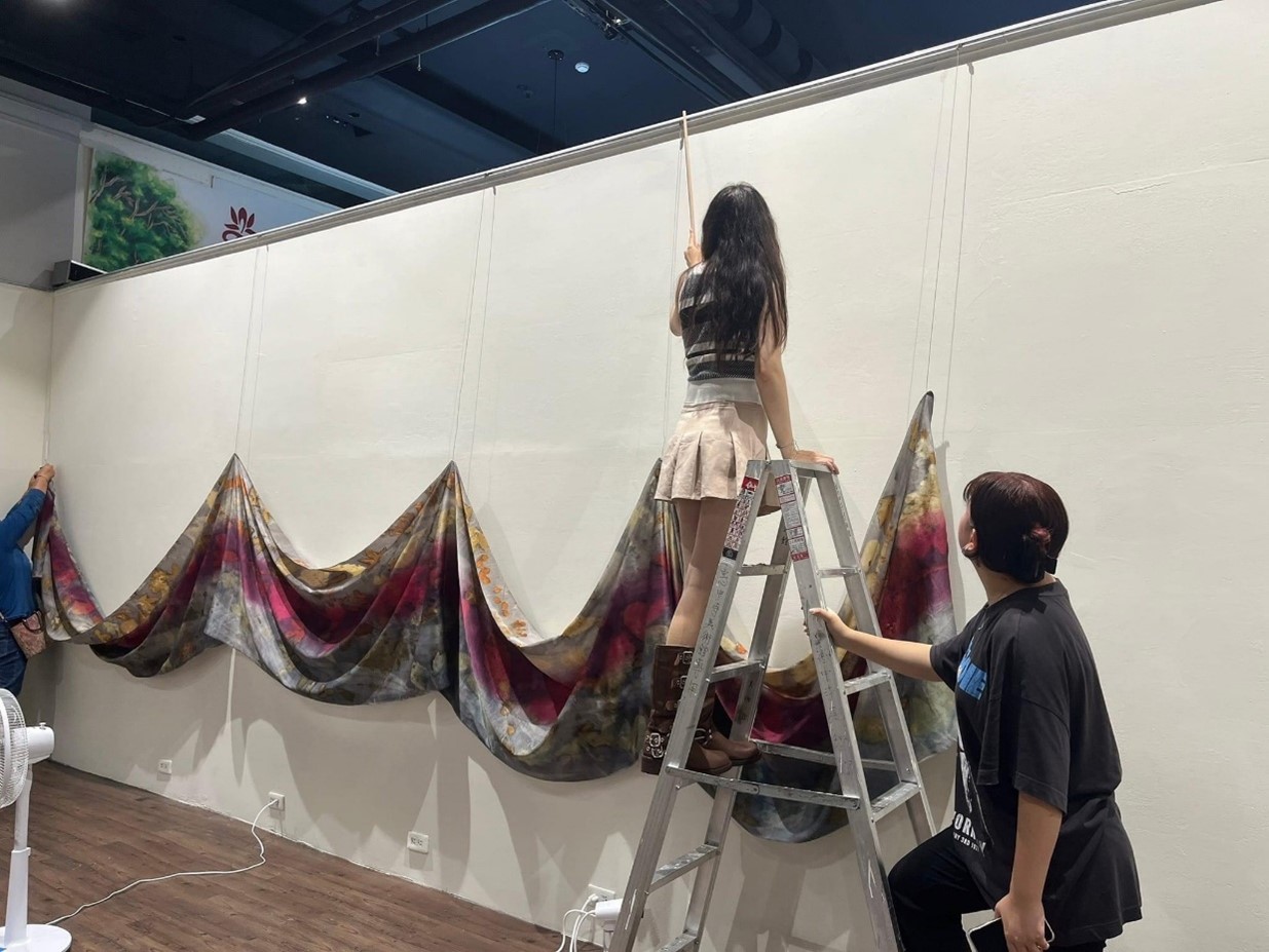 圖為亞大時尚系同學,在展場進行展品吊掛、定位操作。