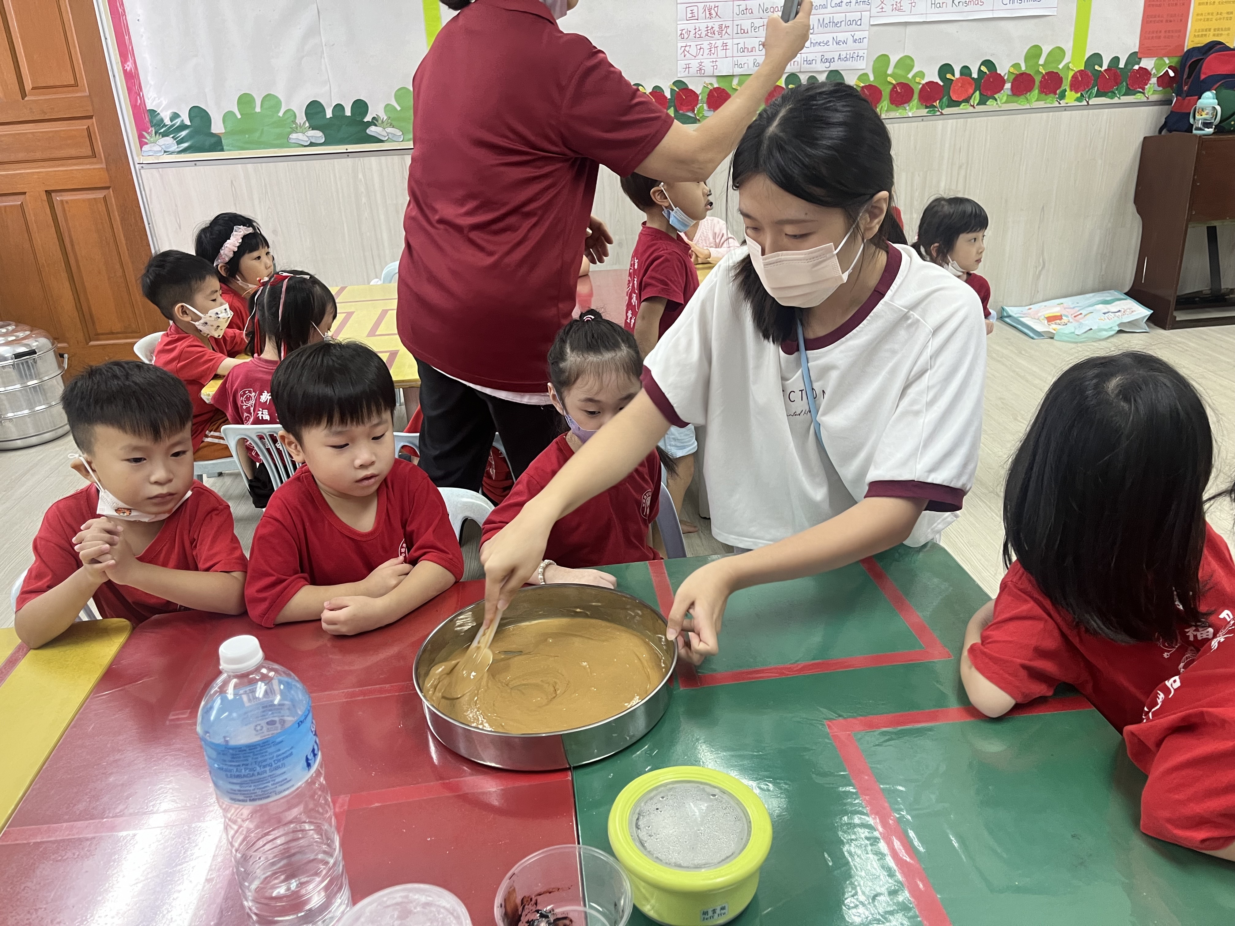 圖為亞大幼教系簡子寧同學,在馬來西亞實習時帶領幼兒製作黑糖糕。