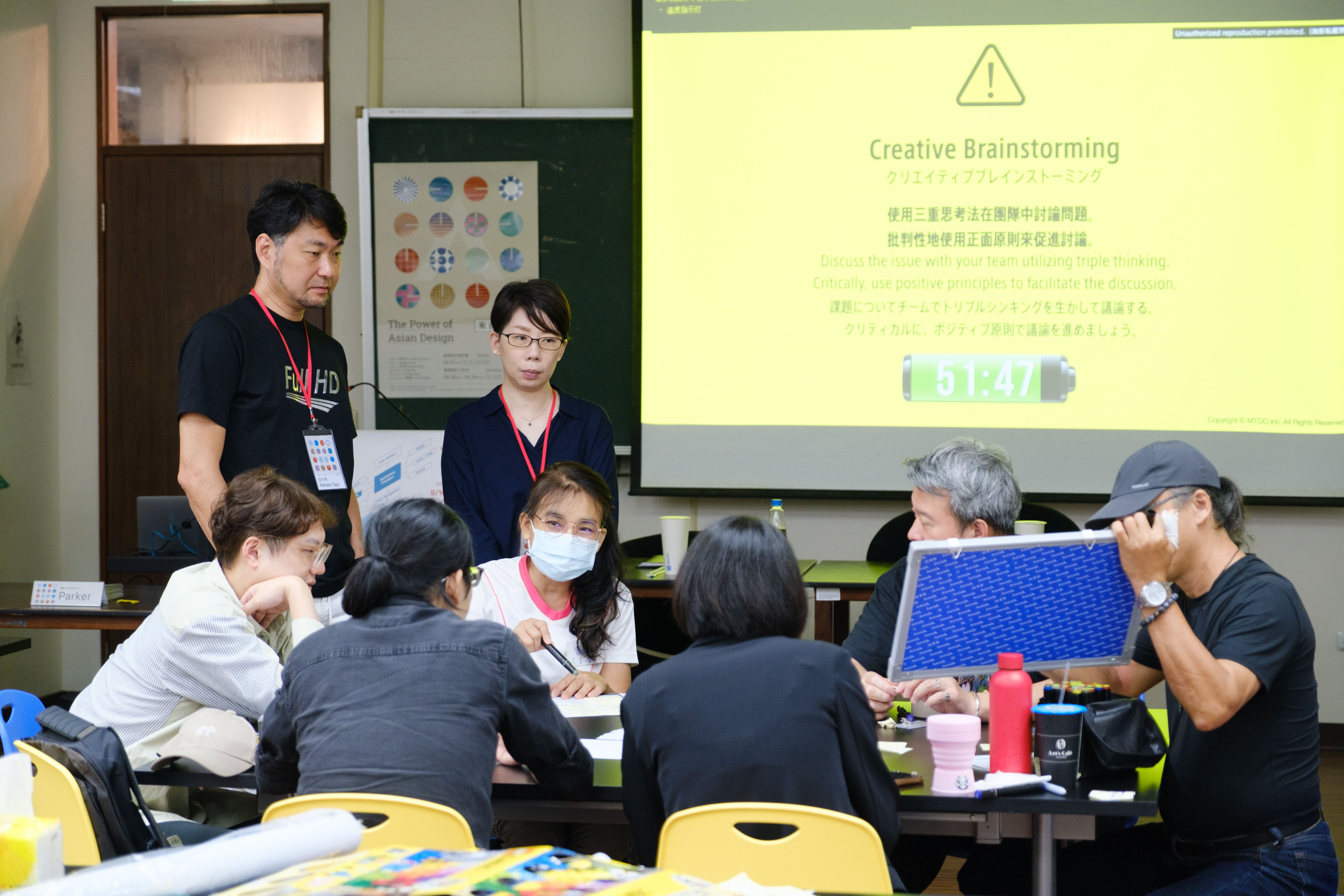圖為日本設計師田子學(站立者左),聆聽教師組學員創意發想討論。