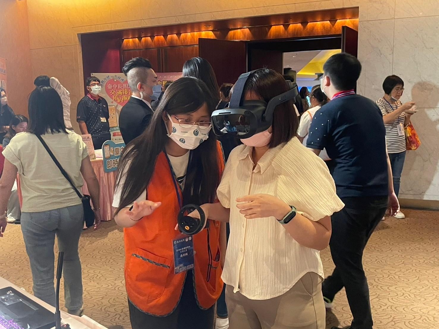 圖為亞大護理學院在「2024台中長照論壇」現場設展,亞大護理系同學引導參觀者,體驗高齡失智照顧技巧VR虛擬實境。