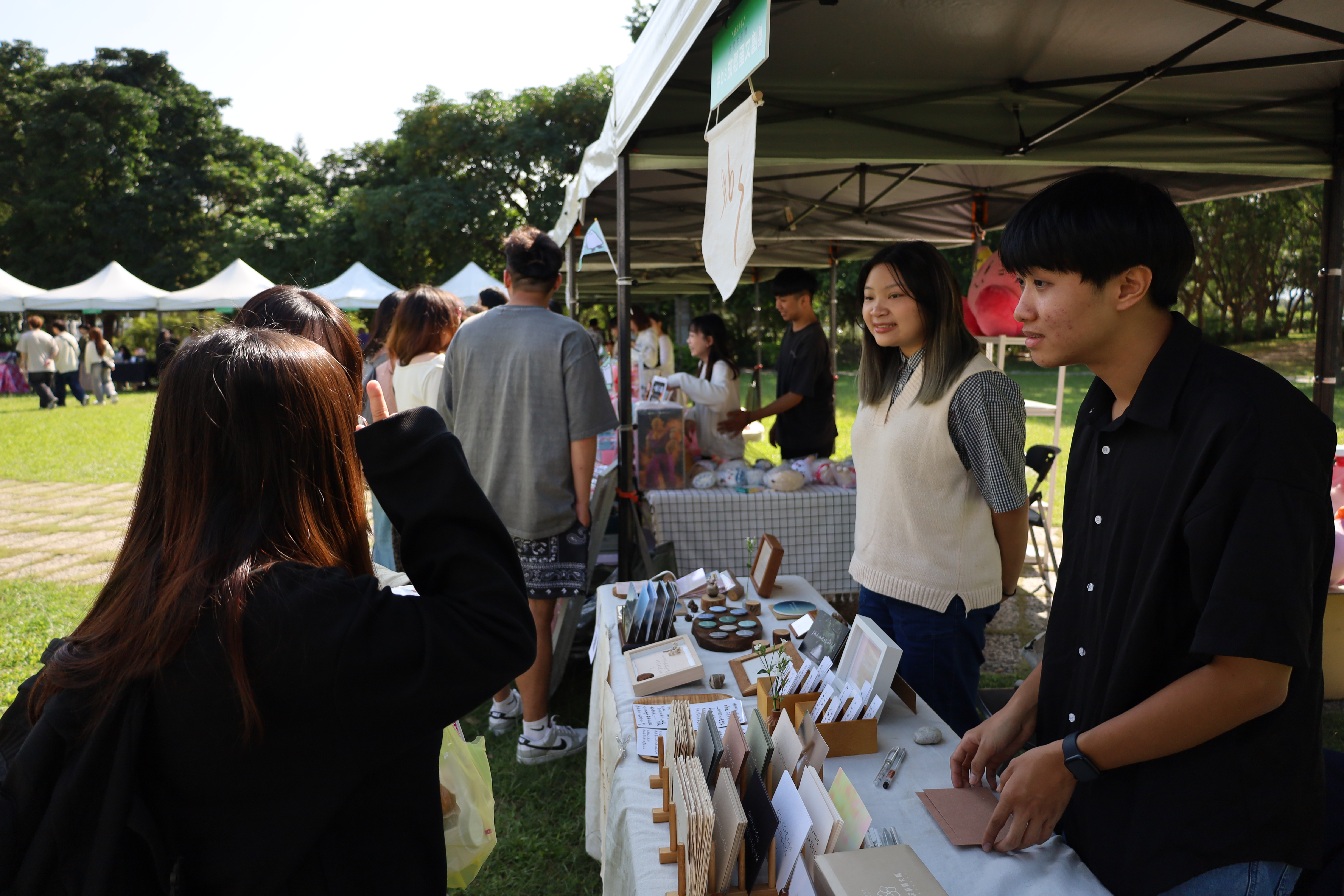 圖為亞大視光系吳柏昇同學(右)，開設的手寫卡片攤位，十分受歡迎。