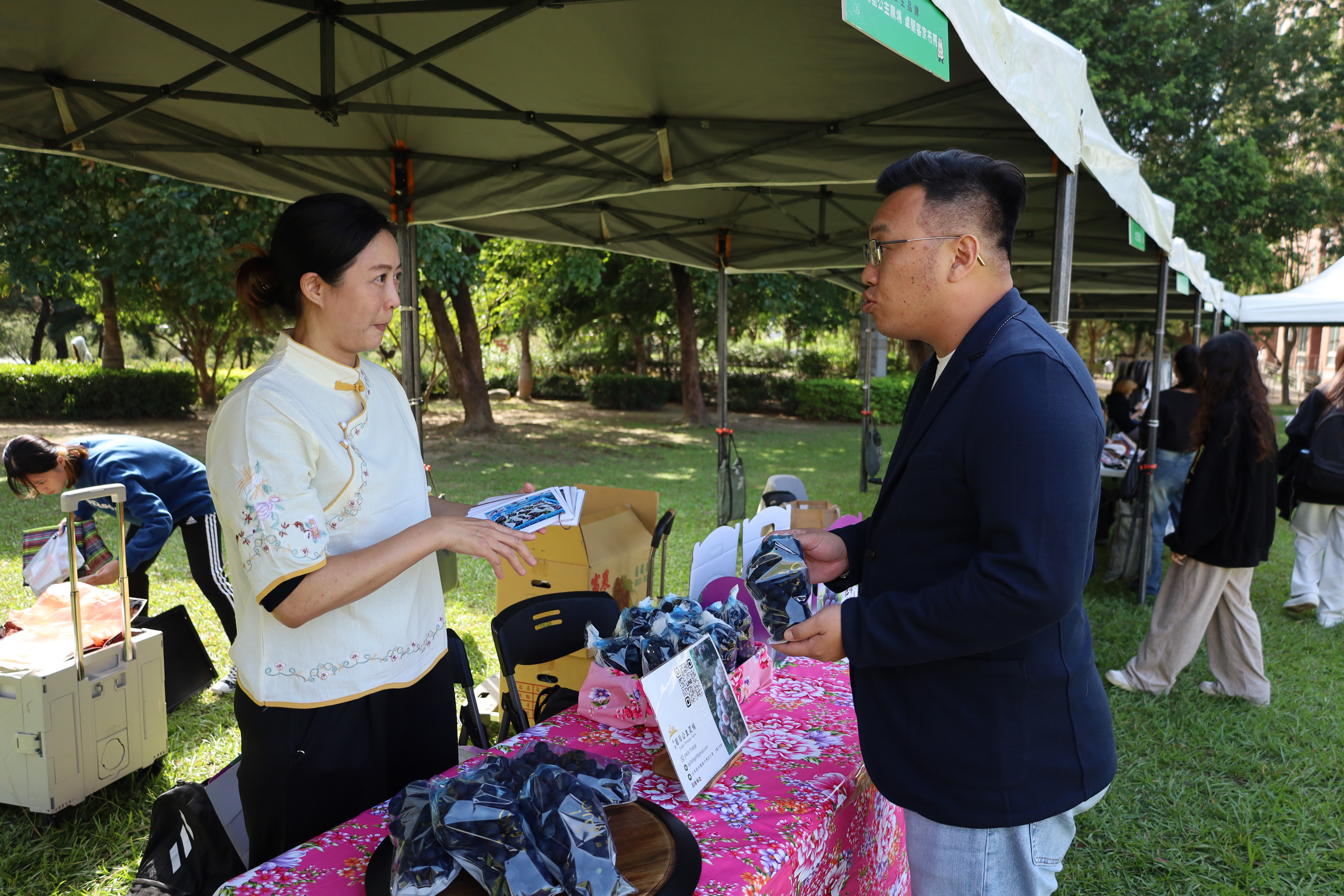 圖為亞大心理系林家蔆同學(左)，向產學長王昭能(右)介紹自家商品。