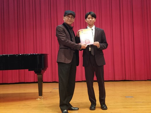 亞大長照系陳柏宏同學(右),獲「全國學生音樂比賽」口琴獨奏大專組第1名特優,上台接受頒獎。