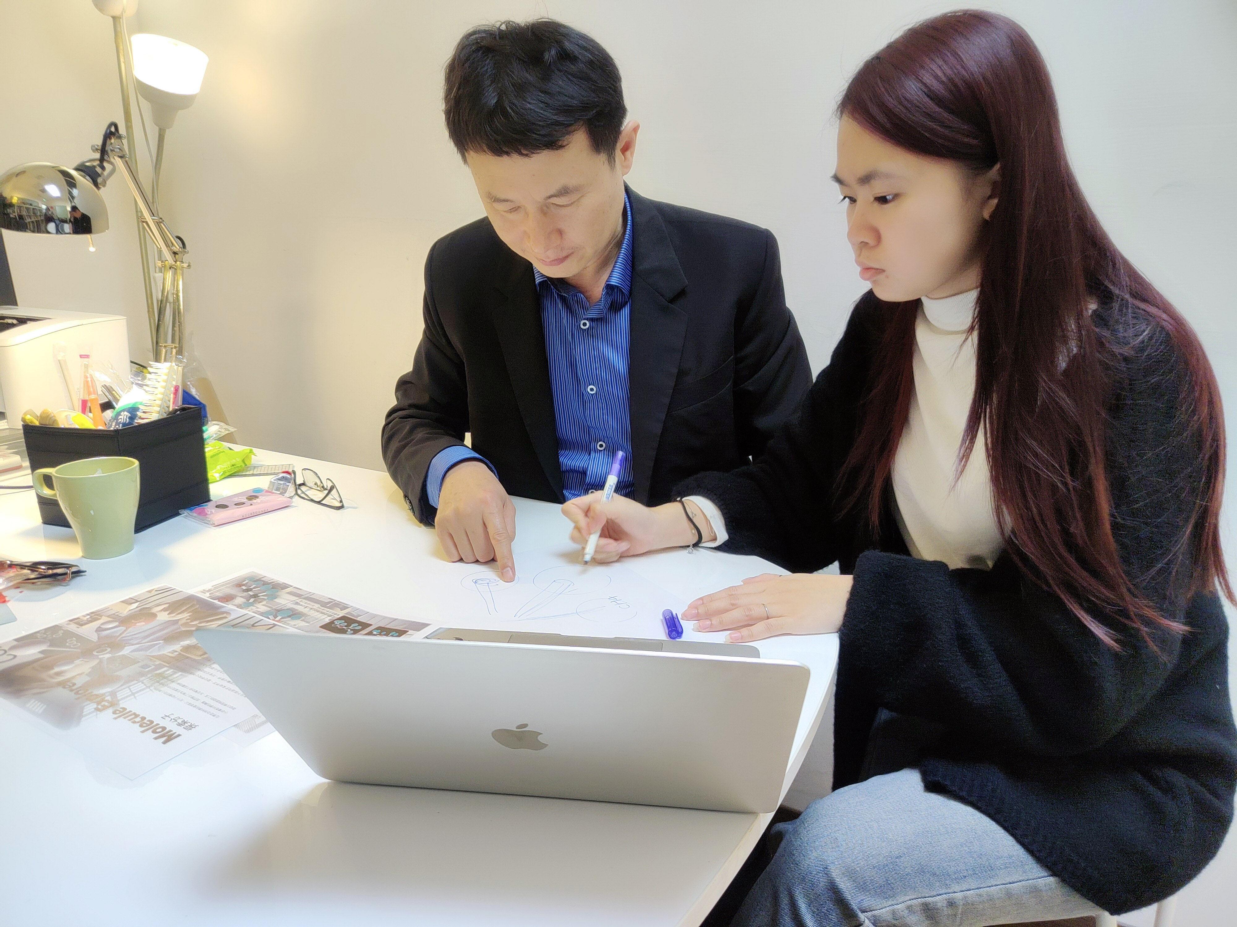 亞大商設系龍希文老師 (左) ，指導商設系黃品瑜同學修正設計作品。