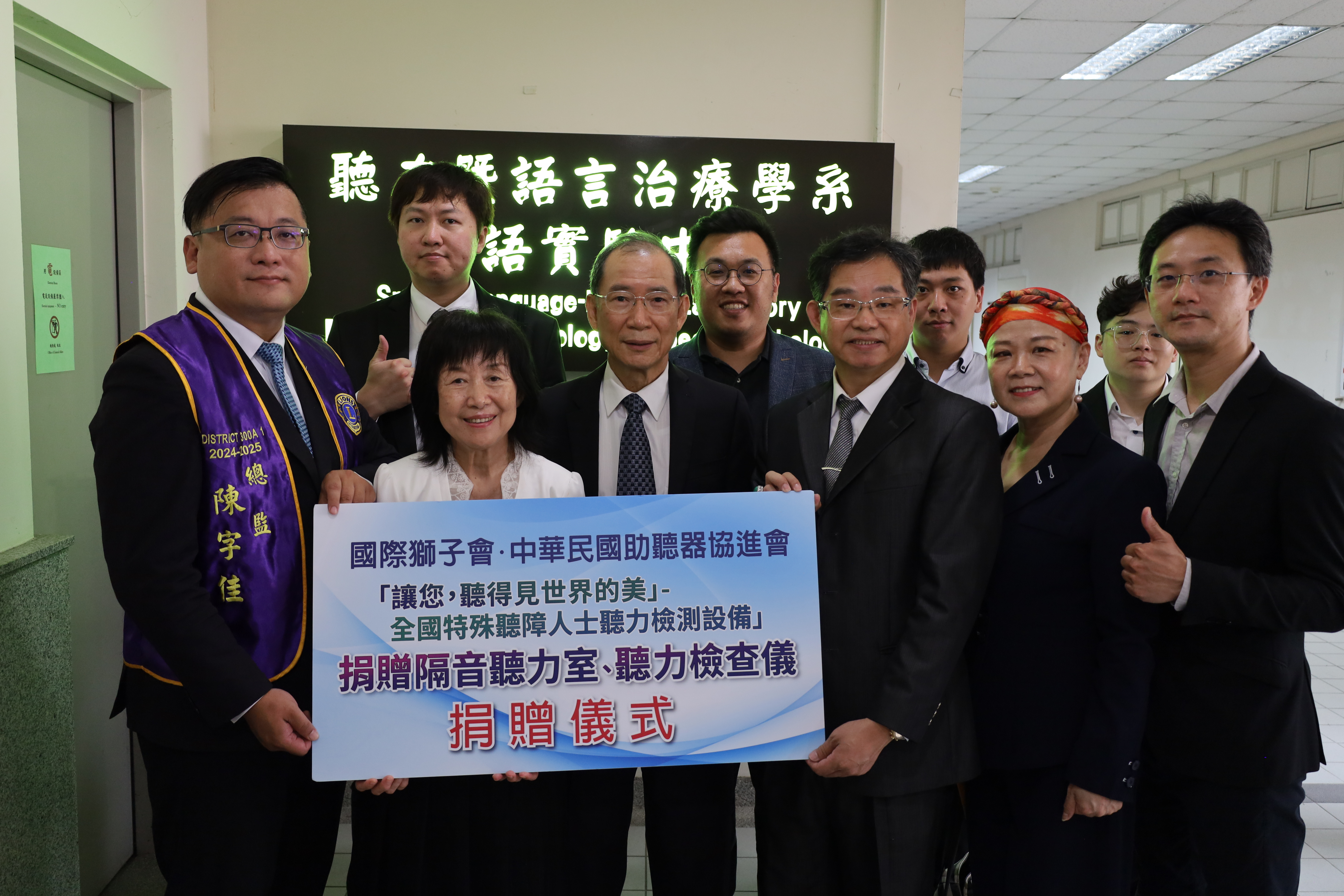 中華民國助聽器同業聯合協進會理事長張峻邦(前排右3)、國際獅子會300A1區總監陳字佳(前排左1)，代表捐贈聽力室、設備給亞大聽語系，由醫健學院長吳俊忠(前排左3)、系主任盛華(前排左2)等，代表受贈。