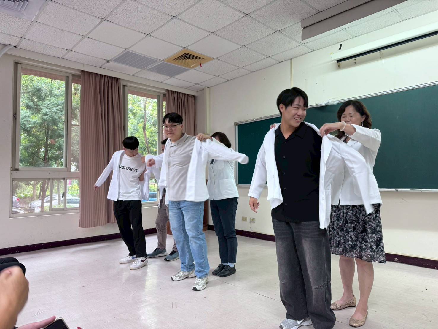 亞大保健系老師,為即將參加營養實習的同學披上白袍。