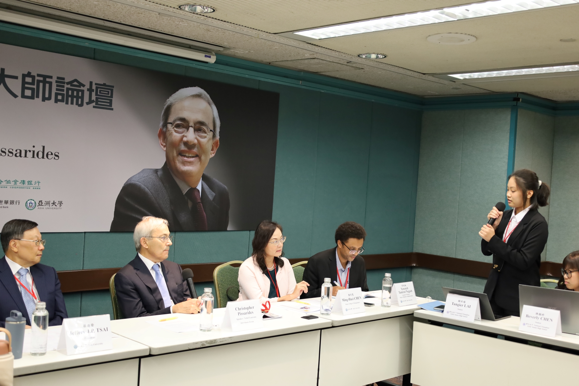 「2025大師論壇」，亞大「策略聯盟高中」彰化女中代表賴承禧(右一)，向諾貝爾大師皮薩里德斯教授（左二）提問請益，親炙大師學習。