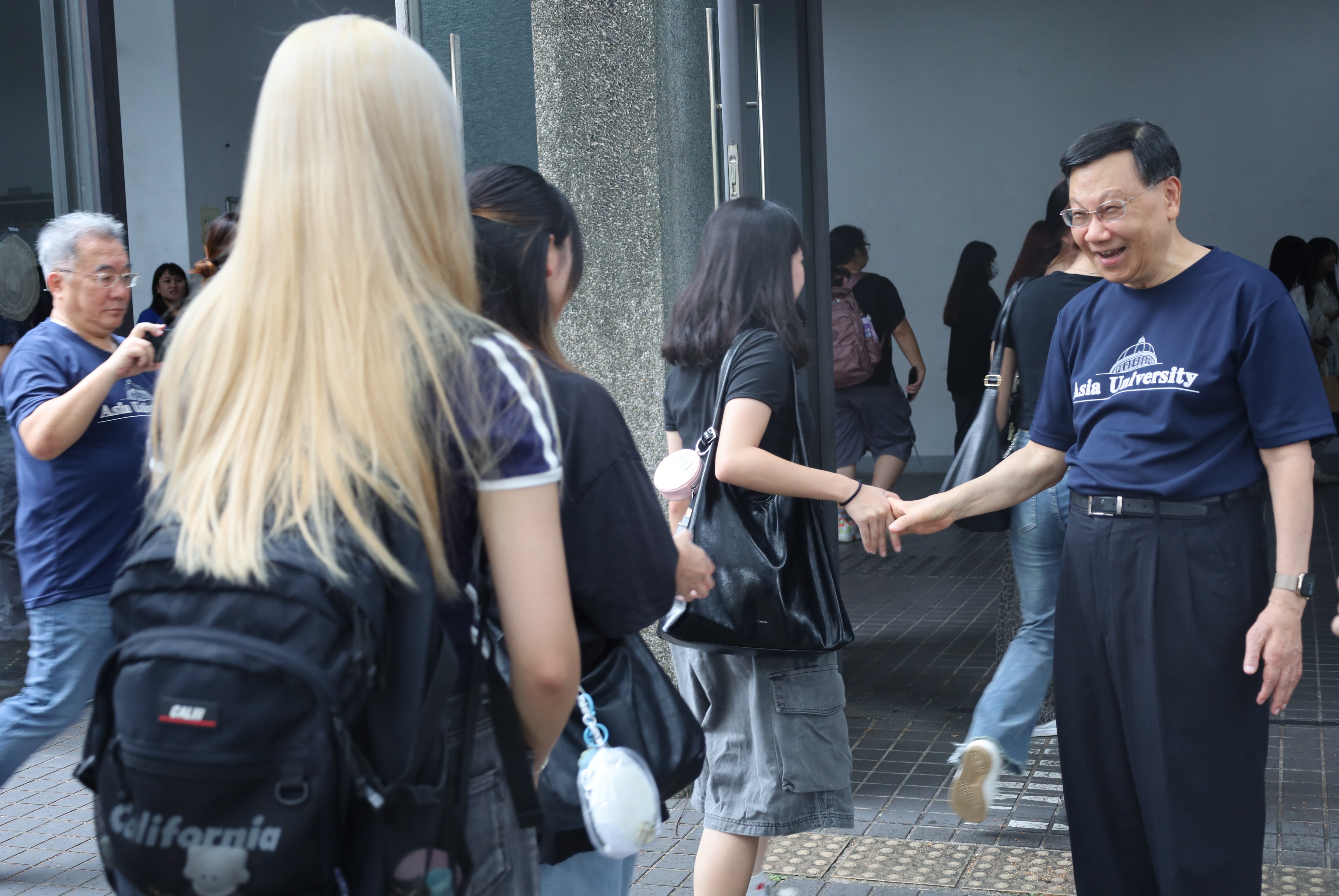 許多新生在始業式時，和亞大校長蔡進發(右)擊掌、握手。